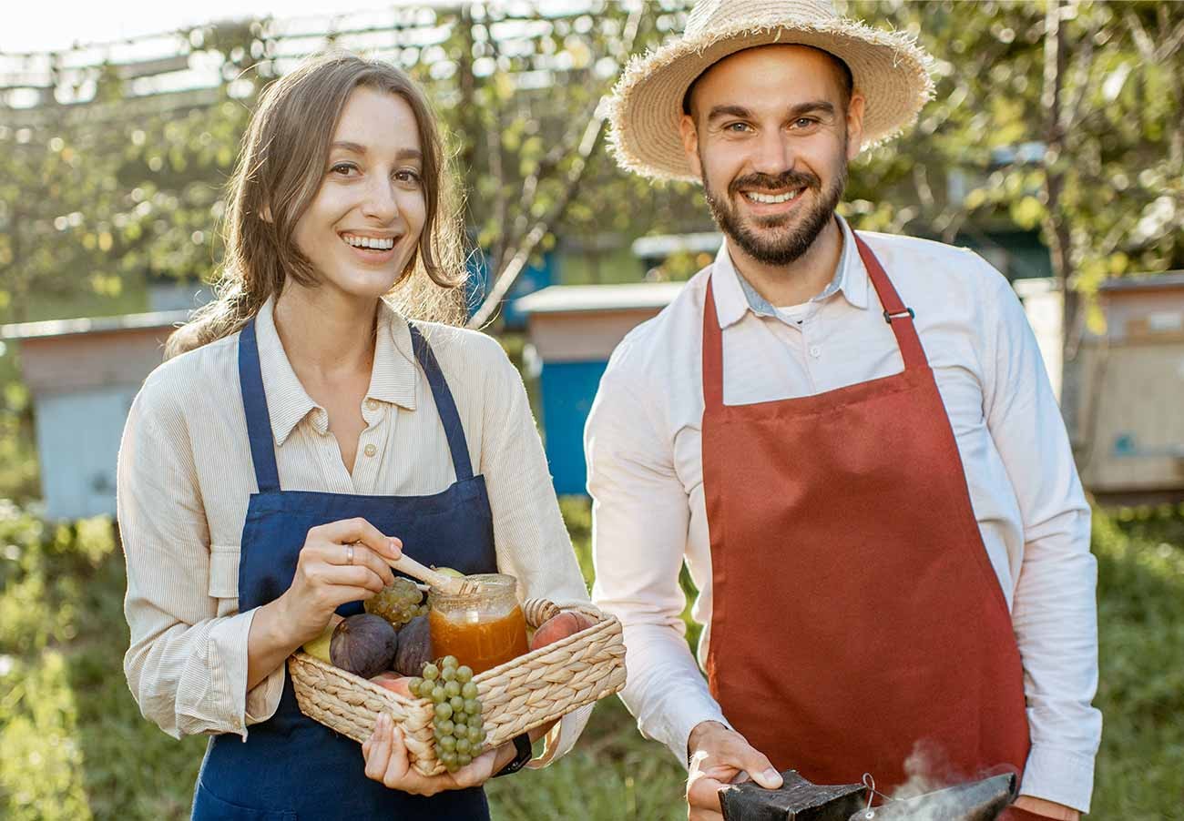 Two beekeepers with a basket of jars