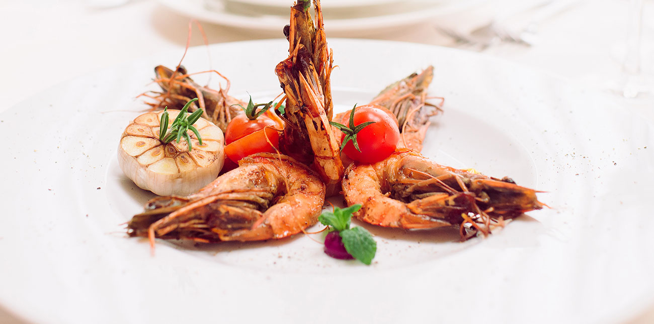Grilled prawns with tomato on a white plate