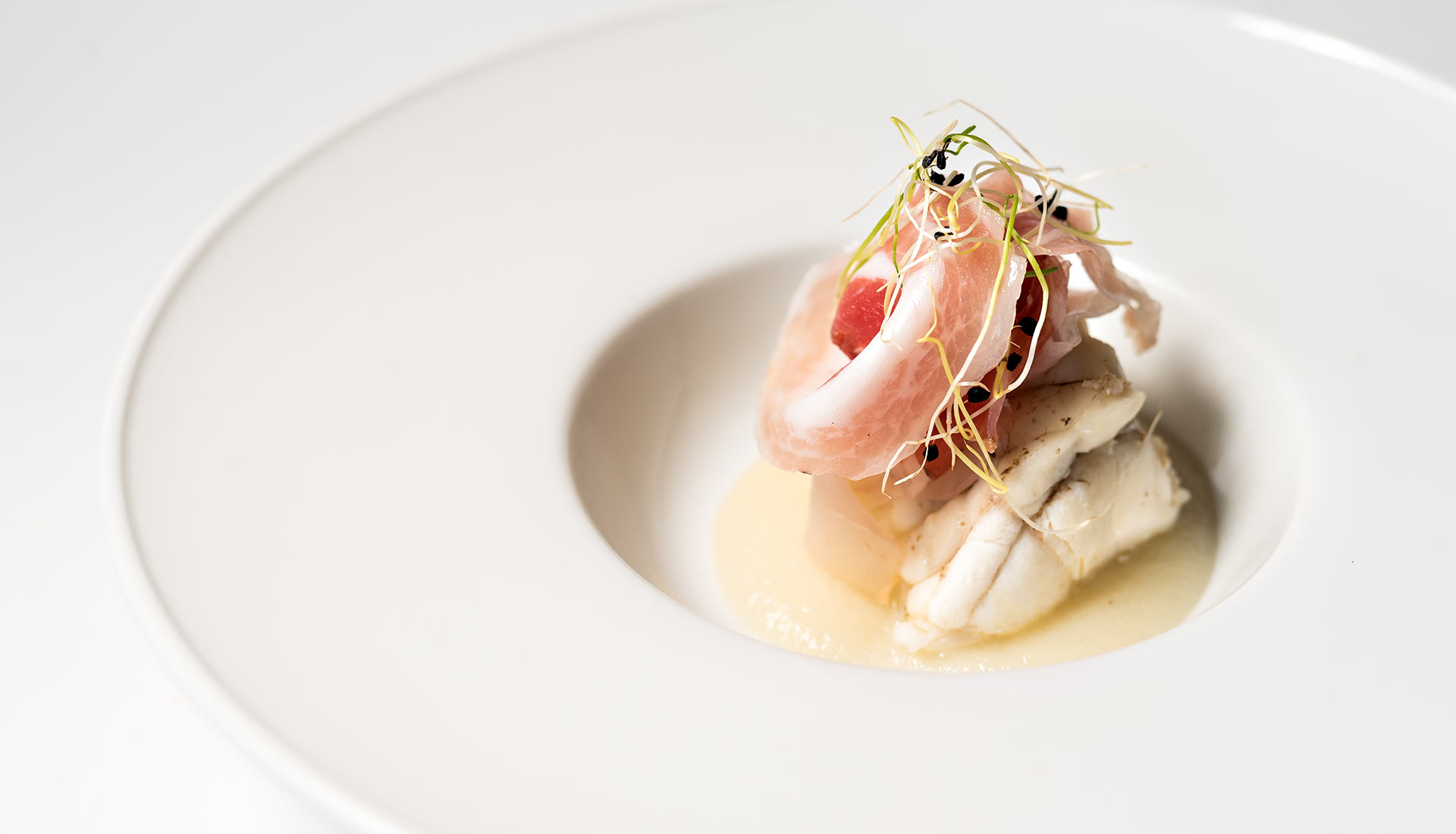 Halibut and crisp ham in a white bowl
