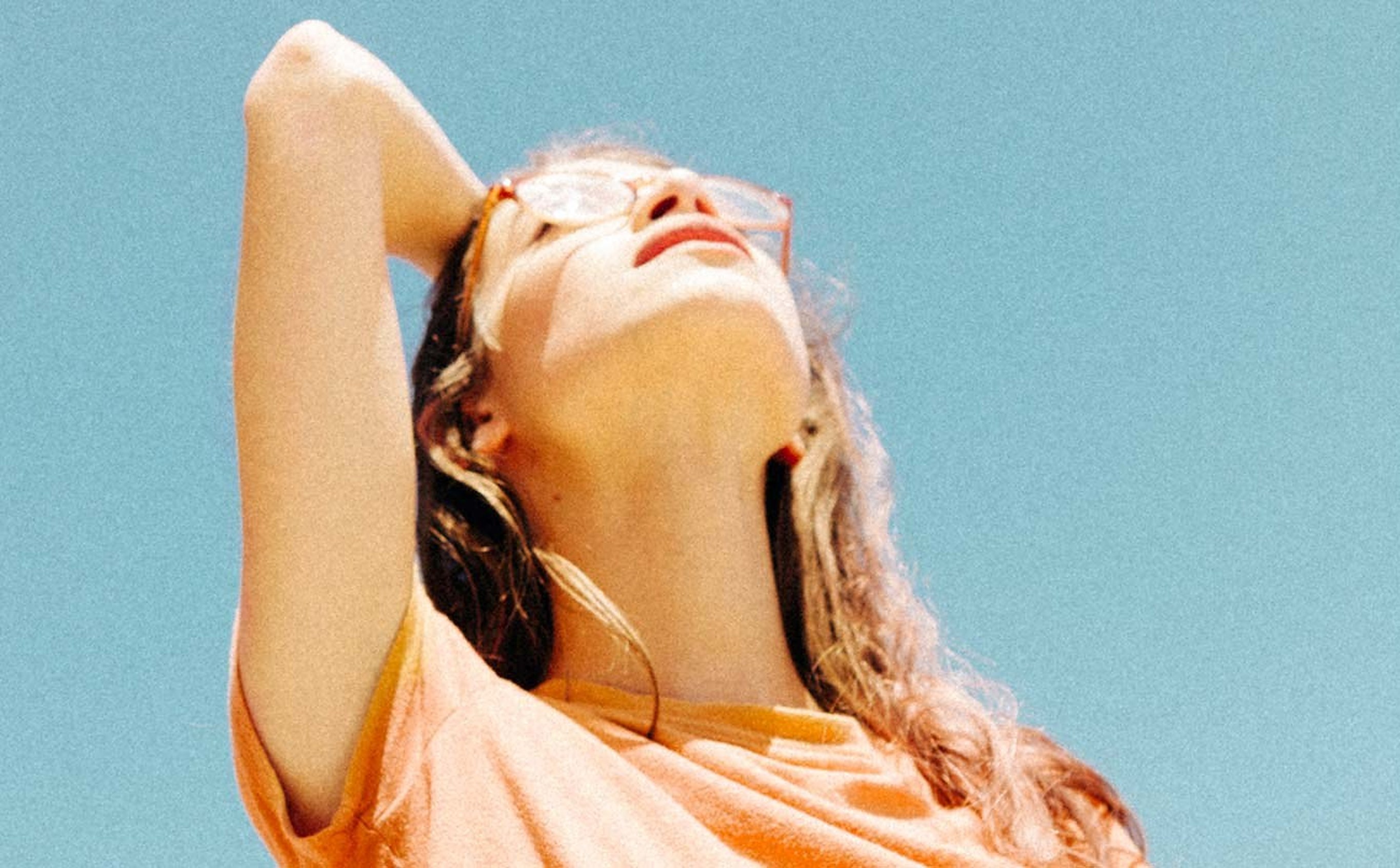 A woman in an apricot top turning her face to the sun
