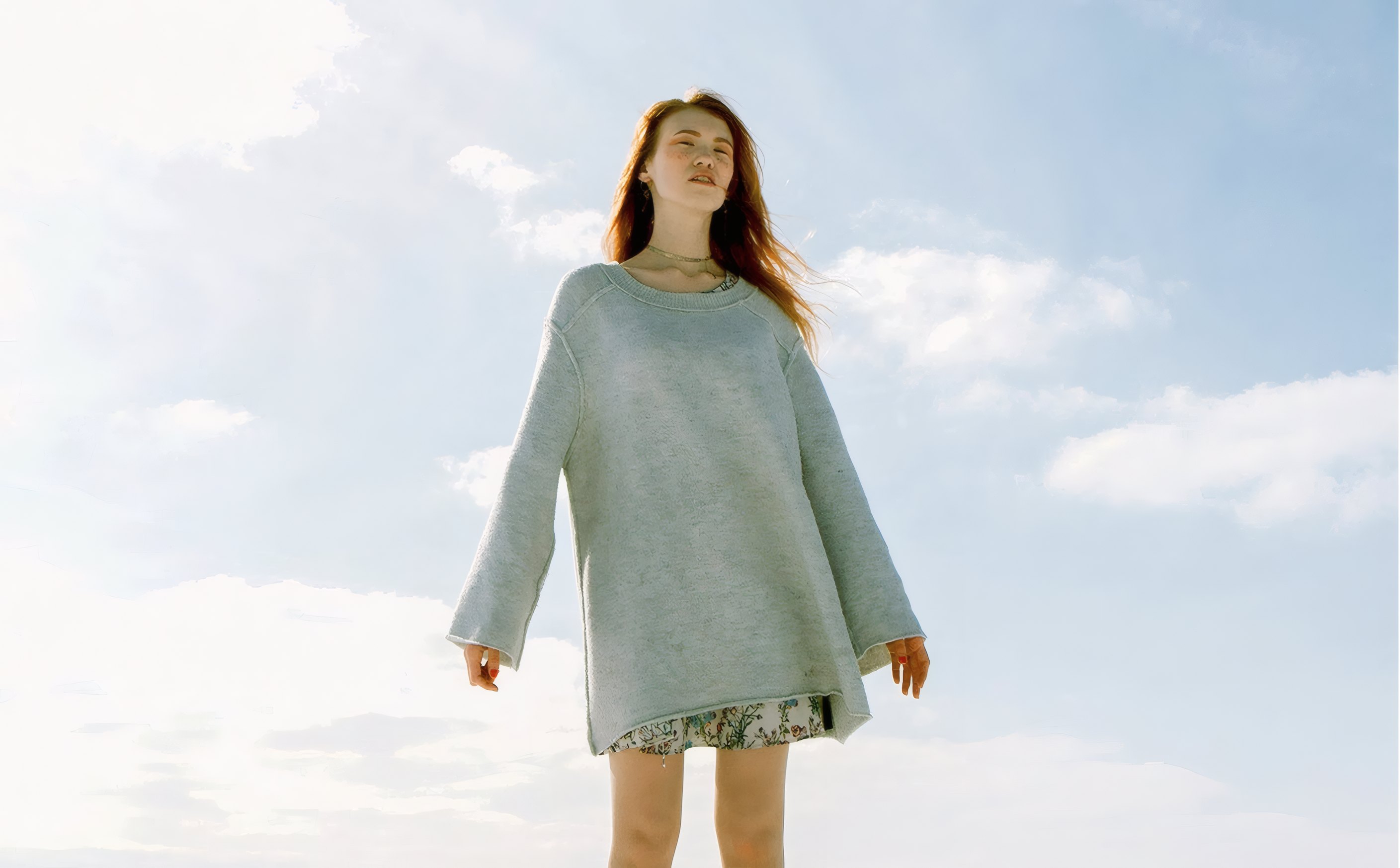 A woman in a sea glass knit dress under a wide sky