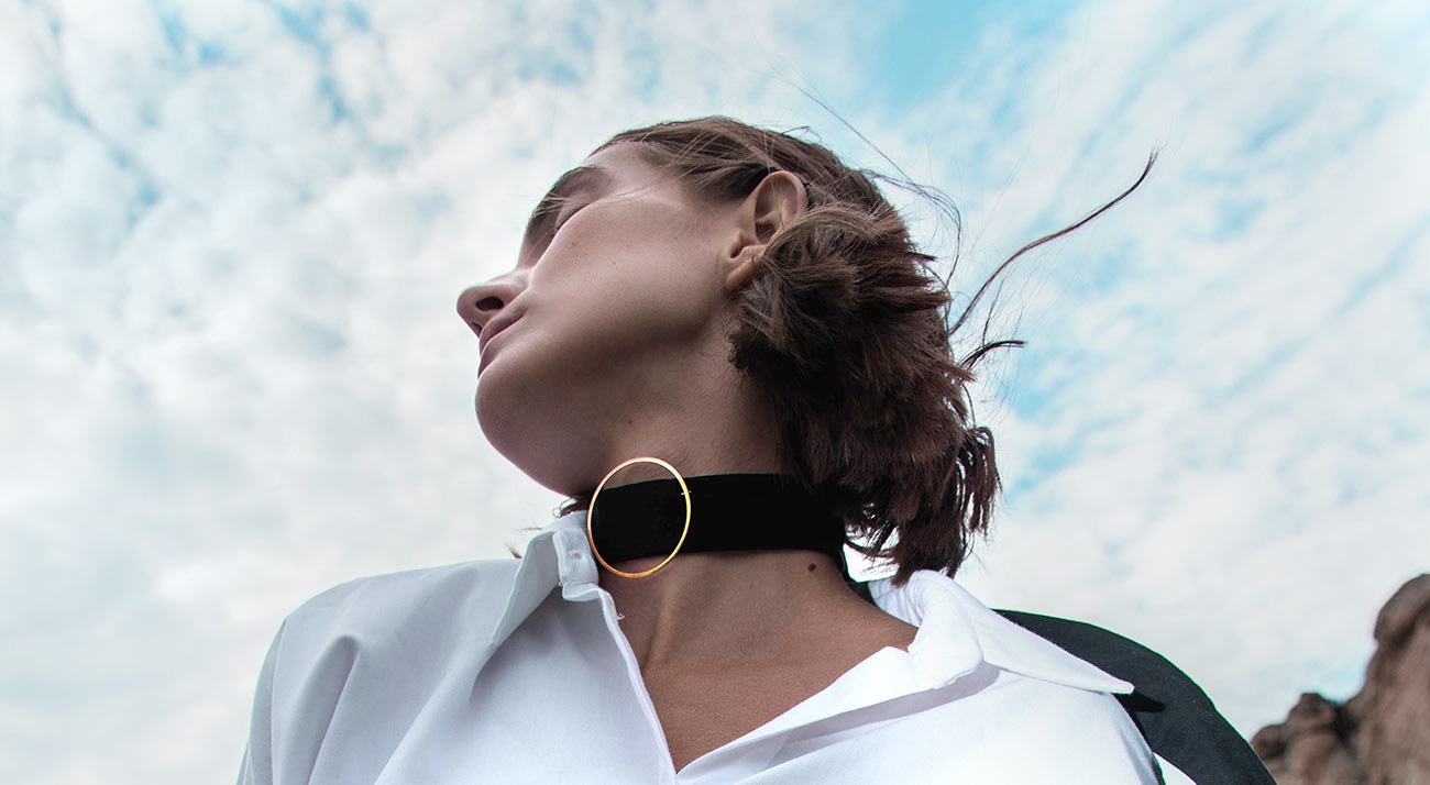 A woman in a white linen shirt under a cloudy sky