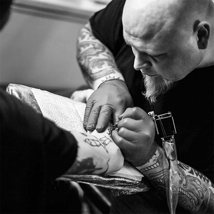 An artist tattooing a client's arm