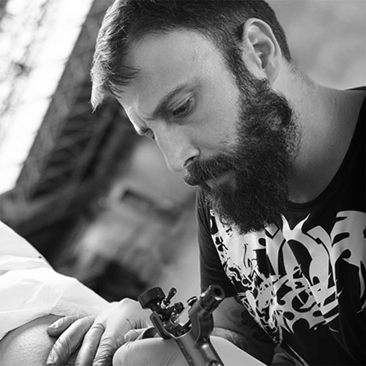 A bearded artist at the tattoo machine