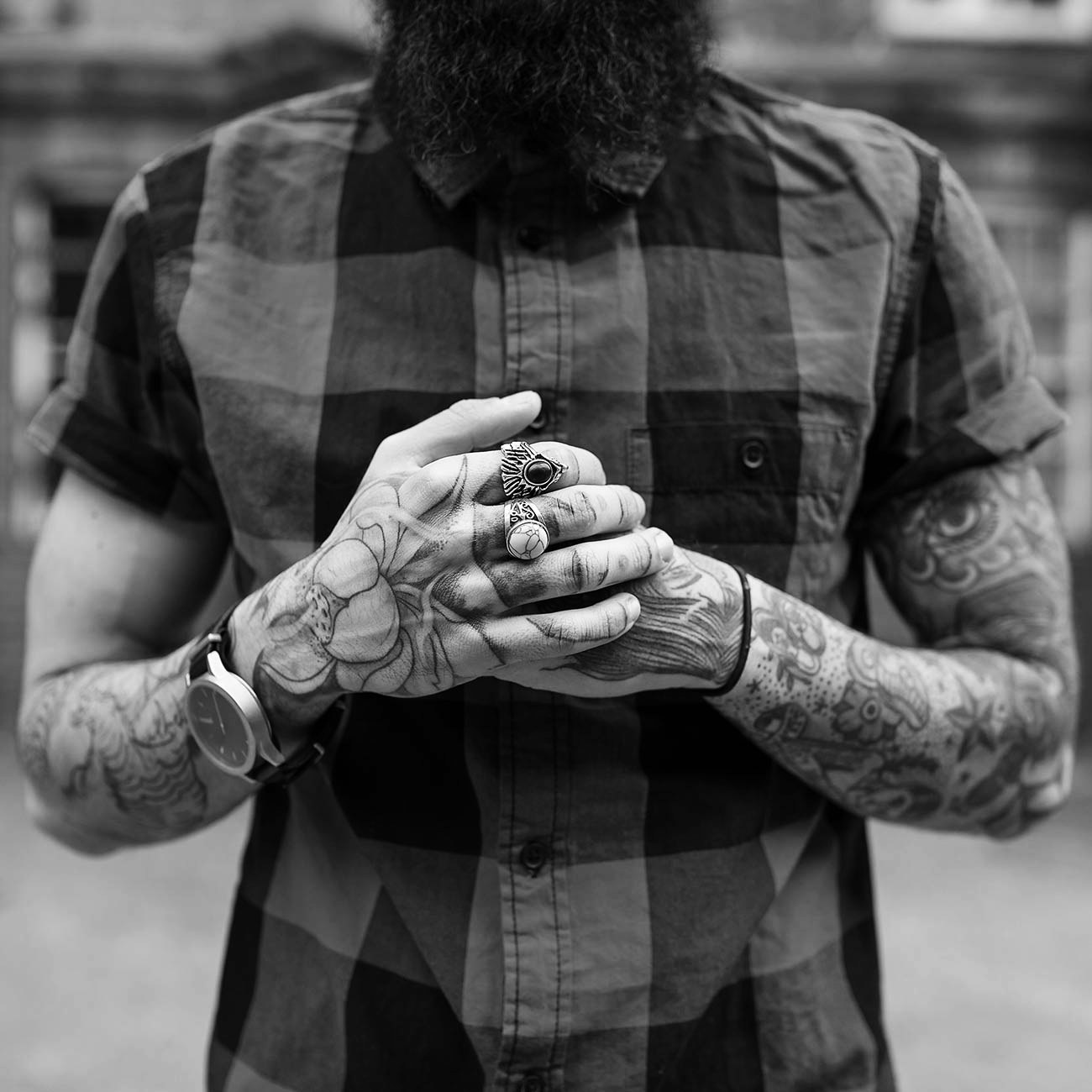 Tattooed hands clasped over a check shirt