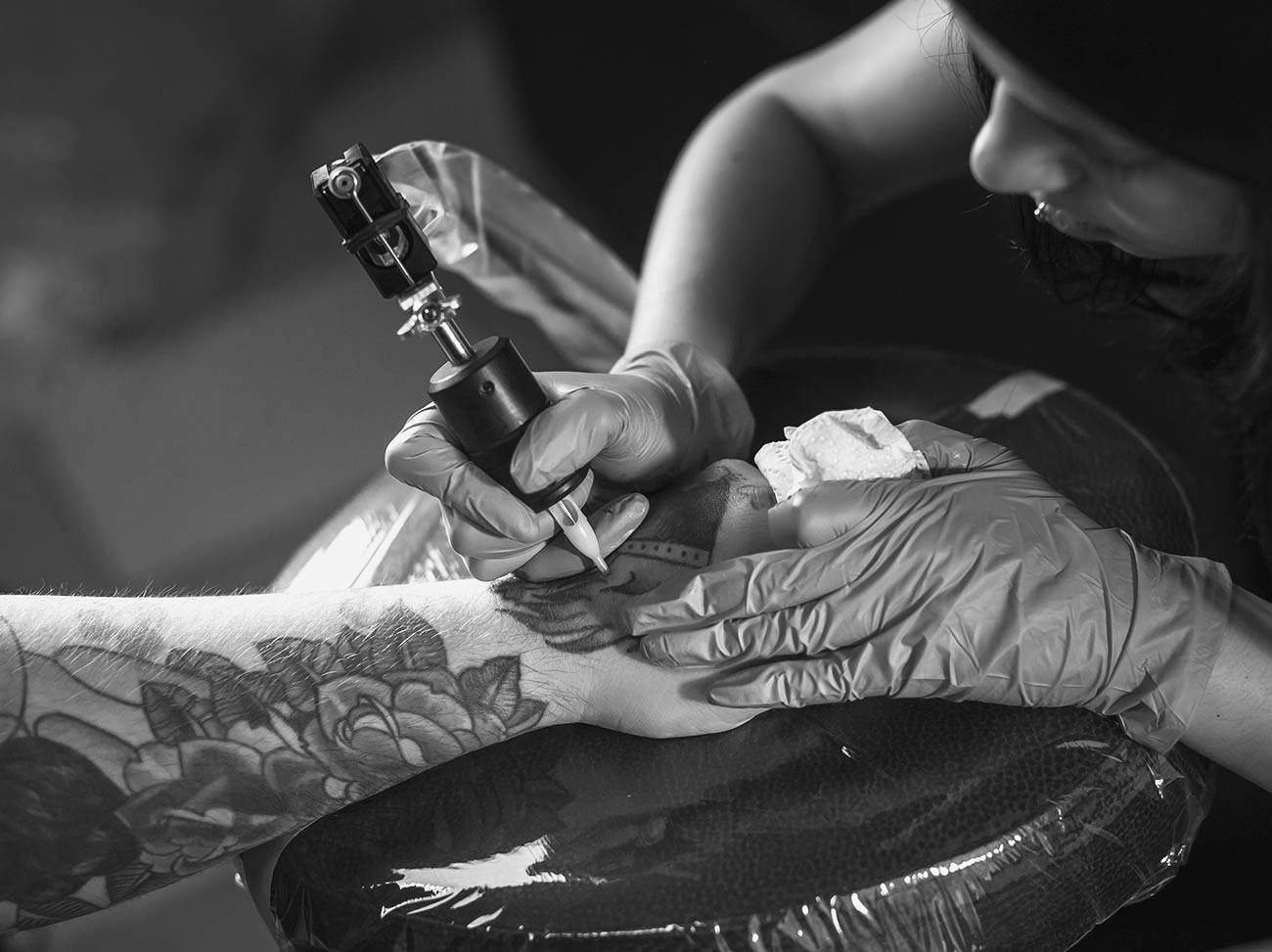 A tattoo artist at work with a machine