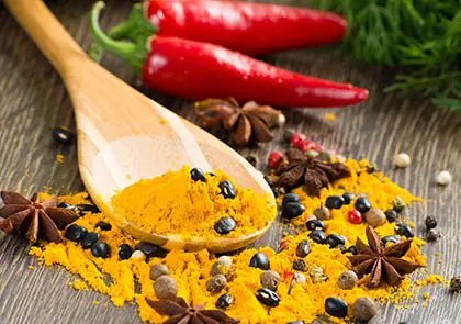 Turmeric on a wooden spoon with chillies