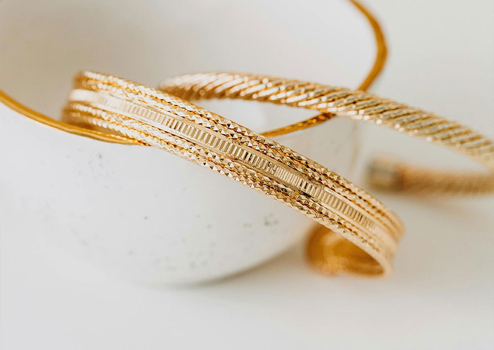 Two gold bangles in a white bowl