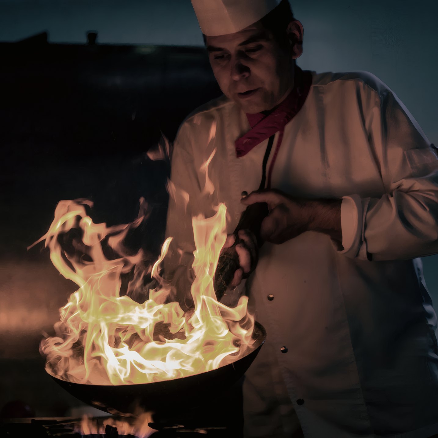The grill master tossing a pan over the flame