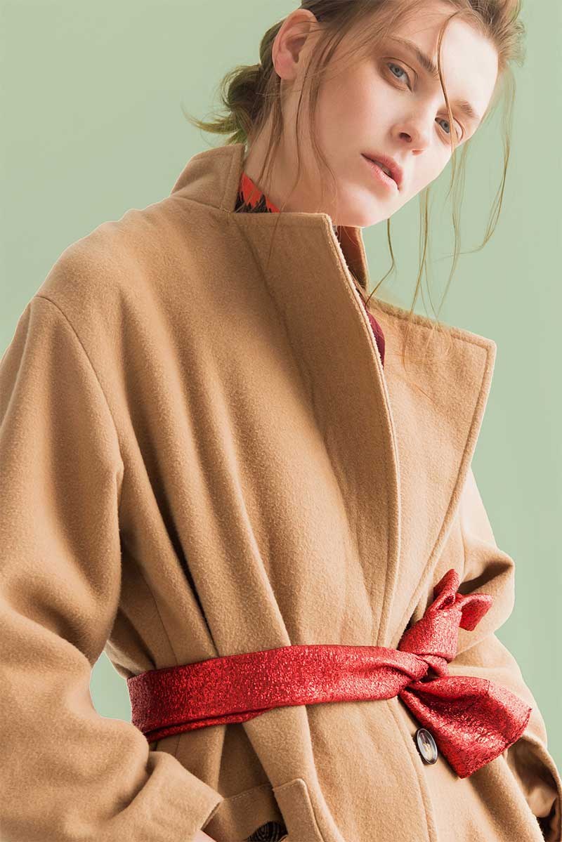 A camel wrap coat with a red satin belt