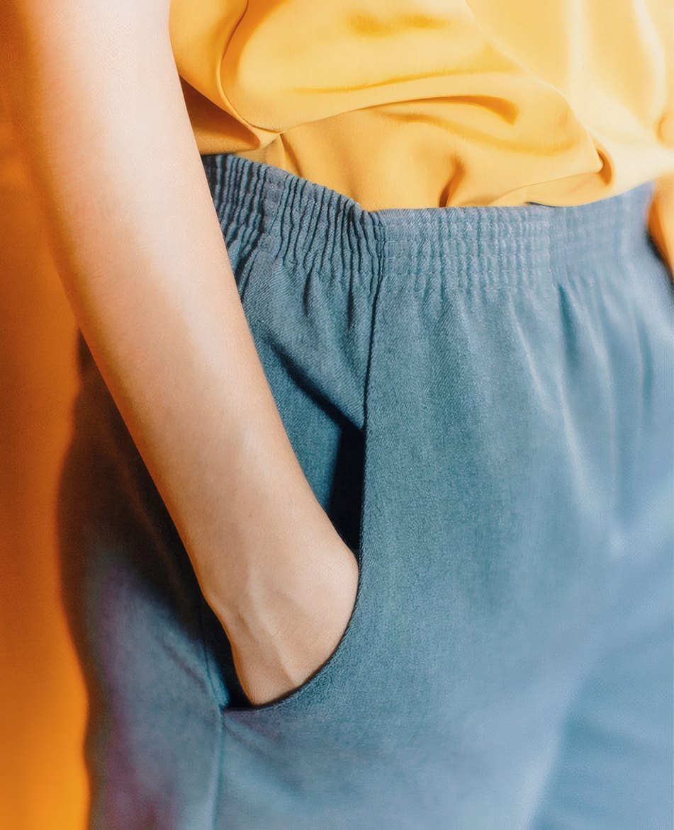 A hand in the pocket of soft blue trousers