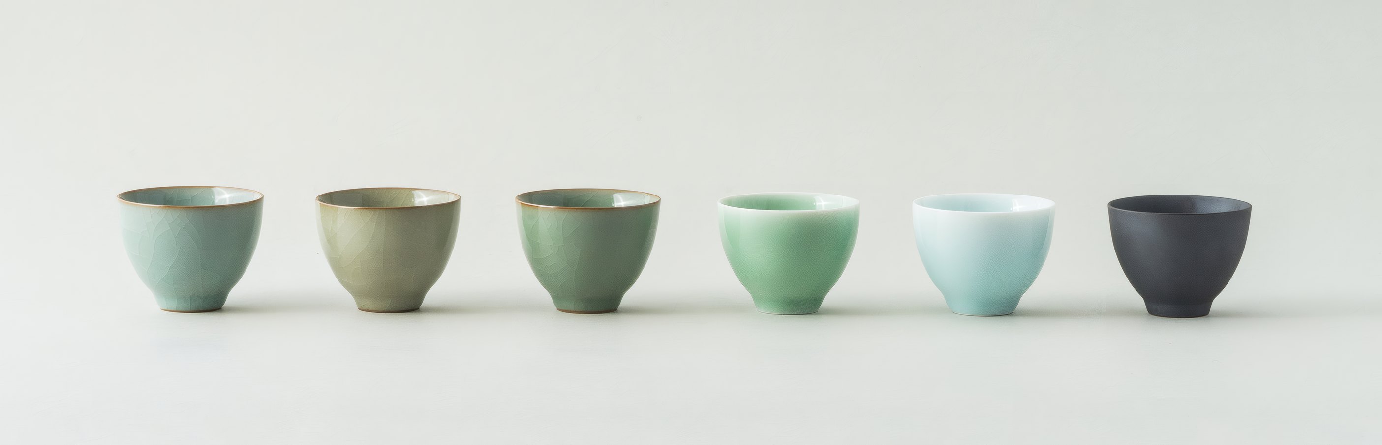 Six glazed tea cups in a row