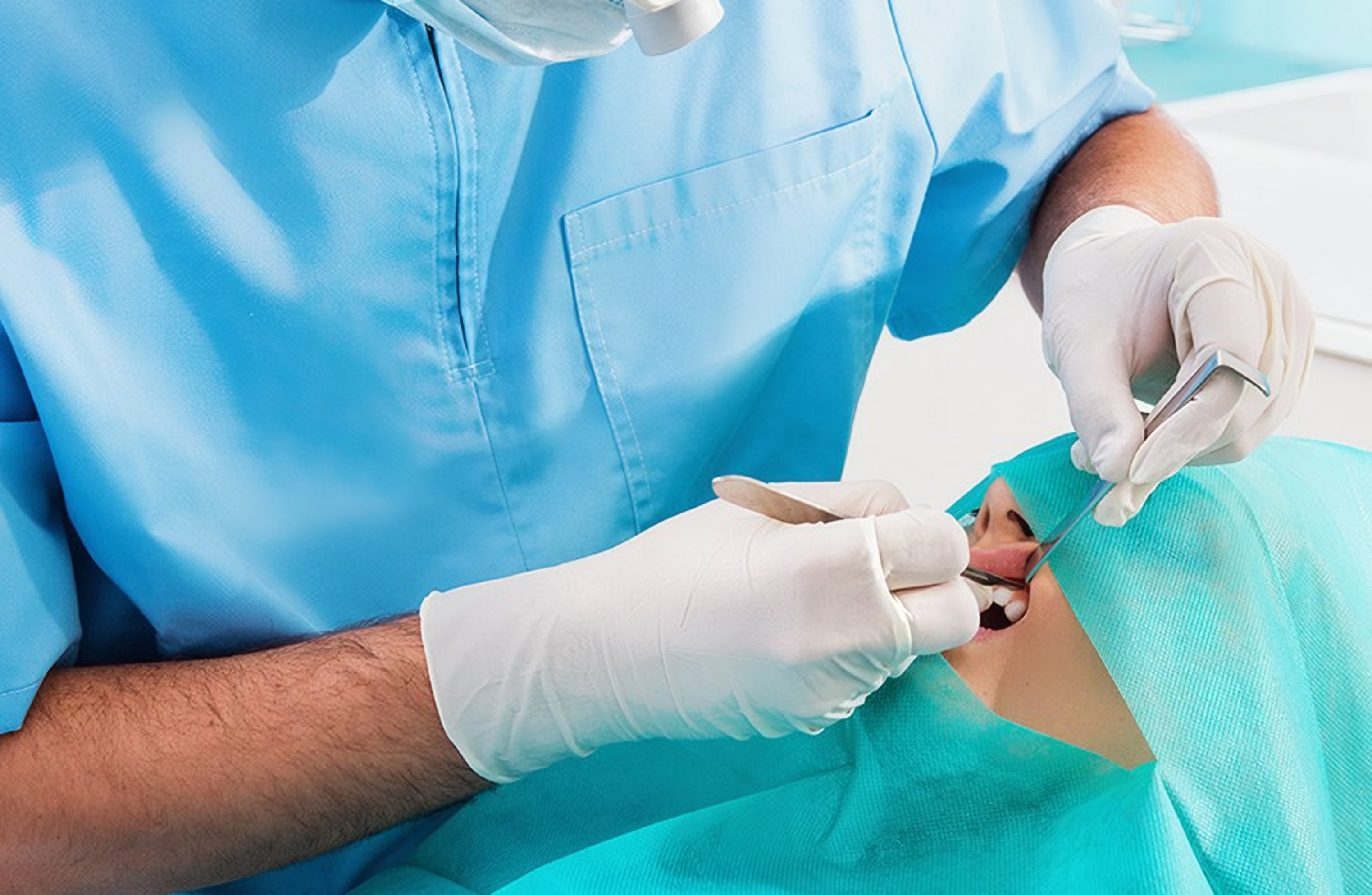 A dentist checks a patient's teeth in the chair