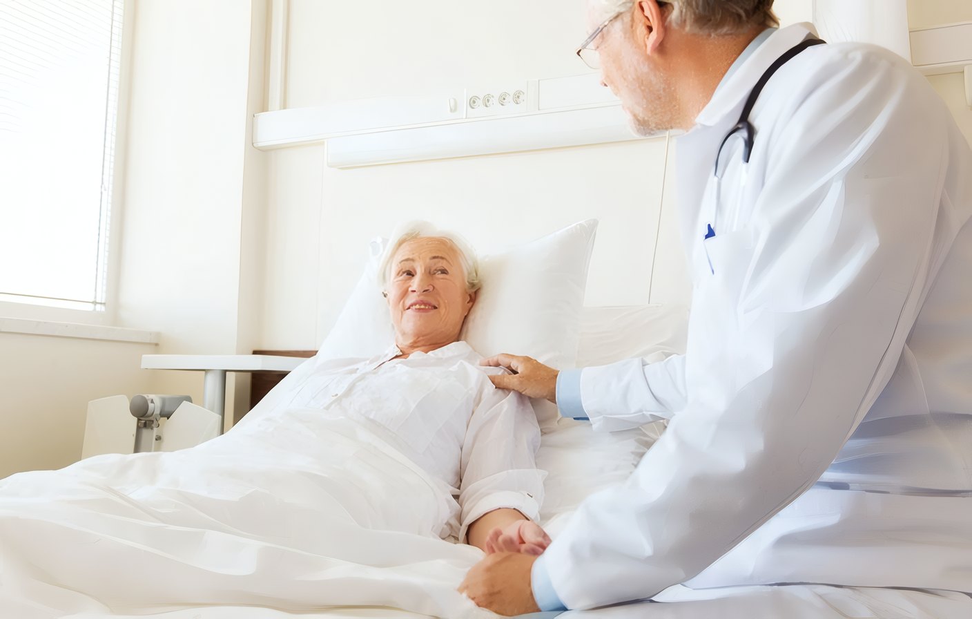 A doctor visiting a smiling patient in her recovery room
