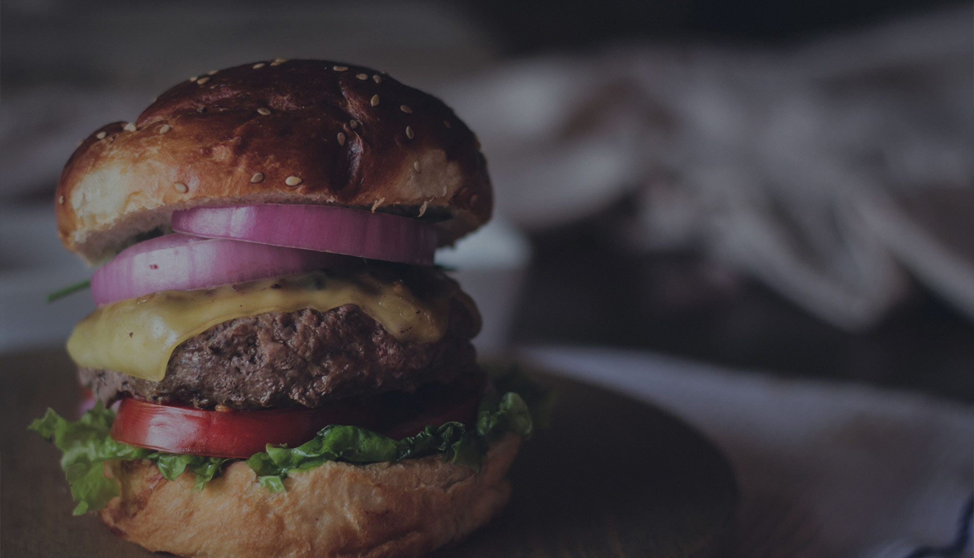 A flame-grilled cheeseburger on a dark board