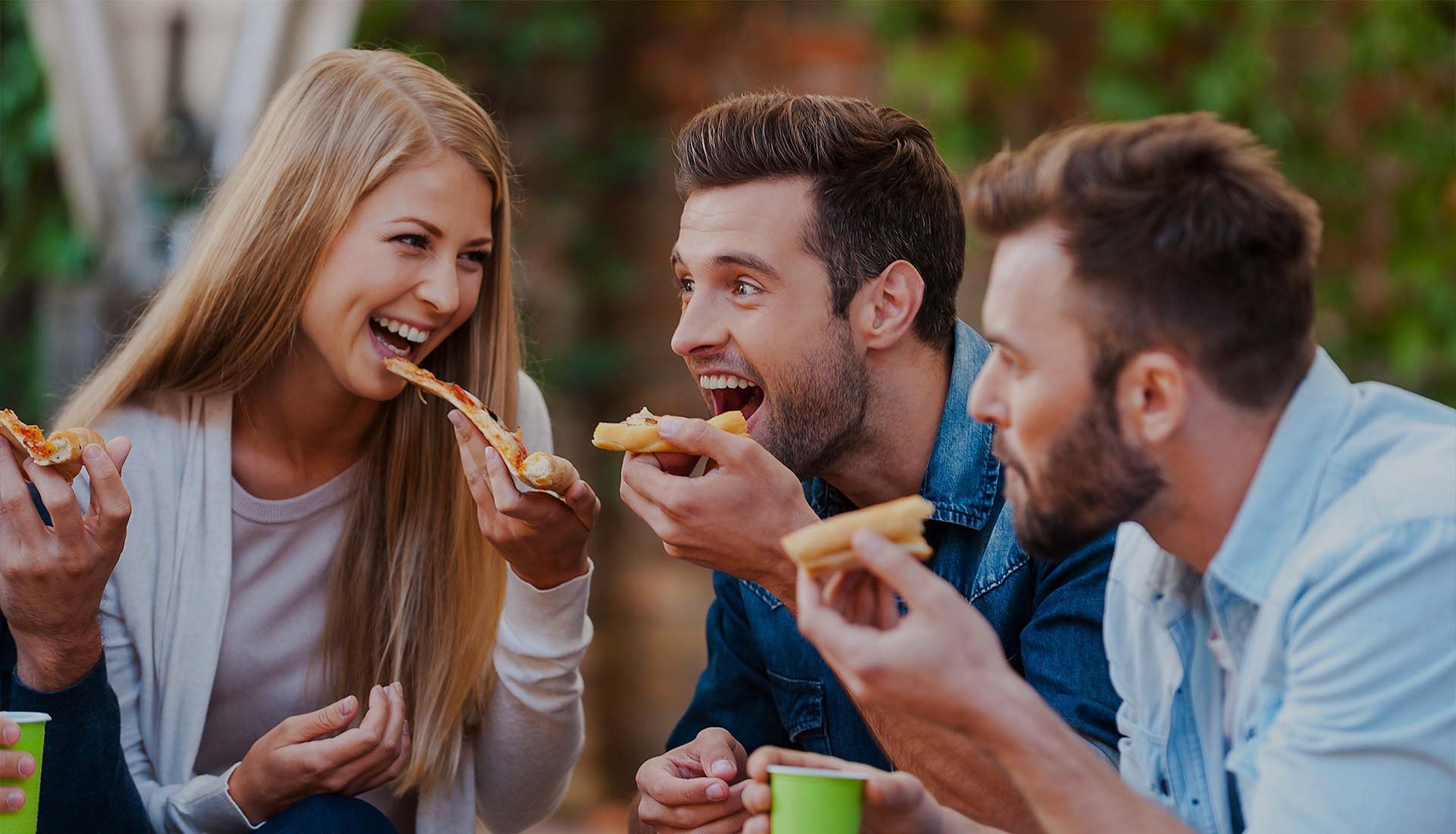 Friends laughing over slices of pizza