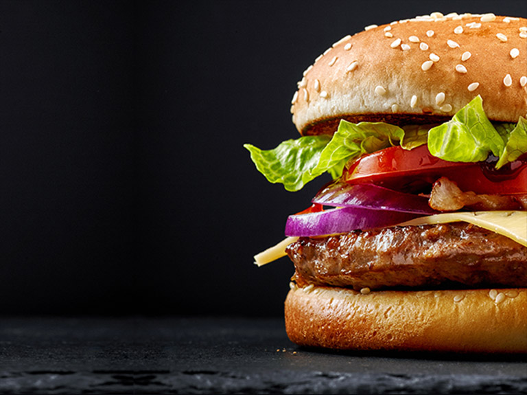 A tall cheeseburger on a black board