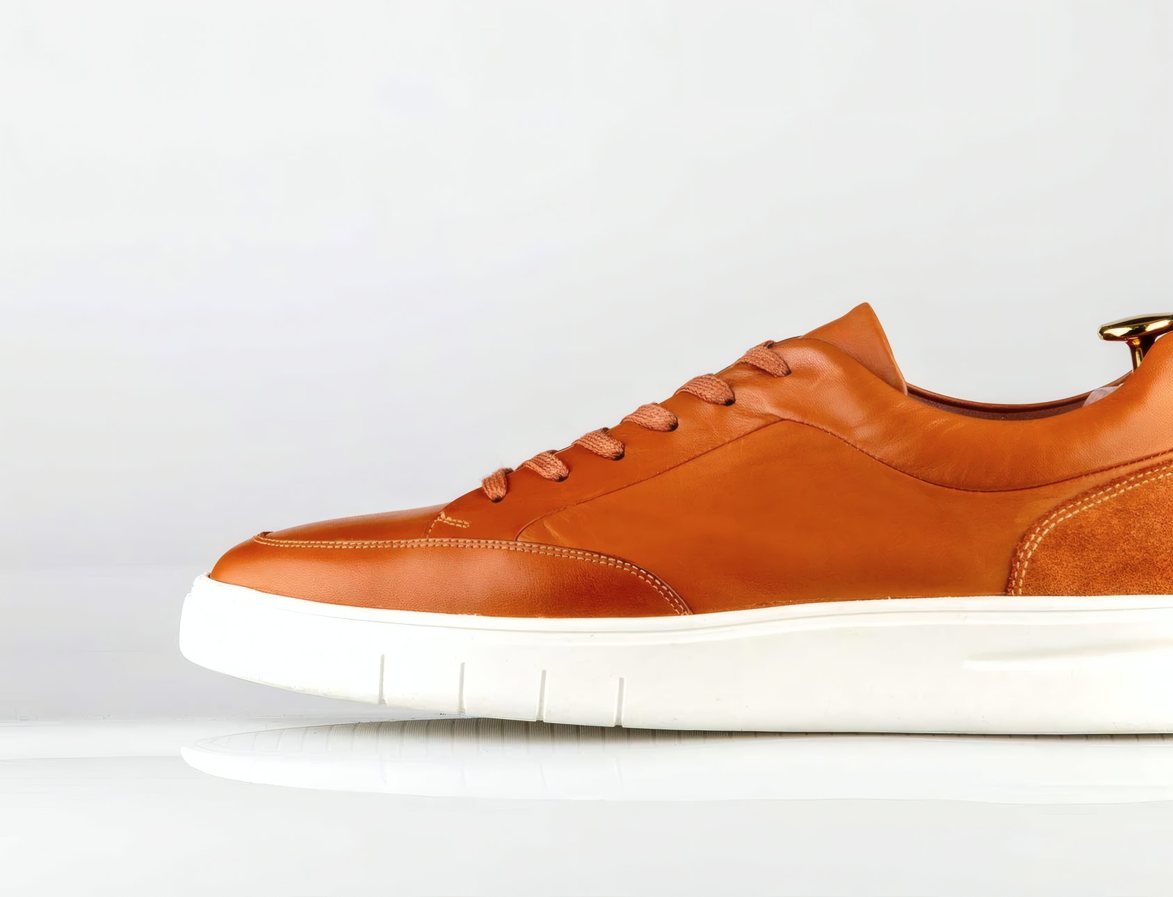 A tan leather sneaker on a white ground
