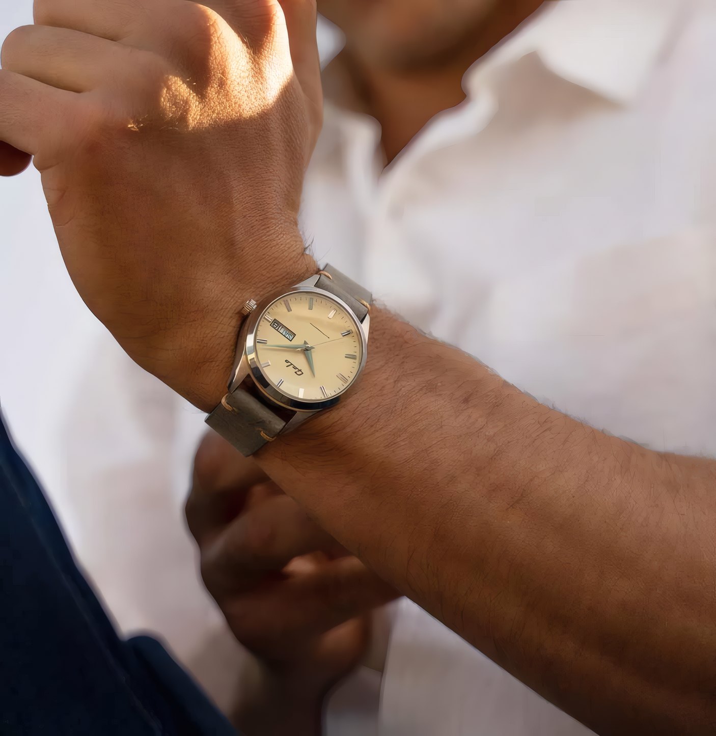 A gold watch on a wrist against a white shirt cuff
