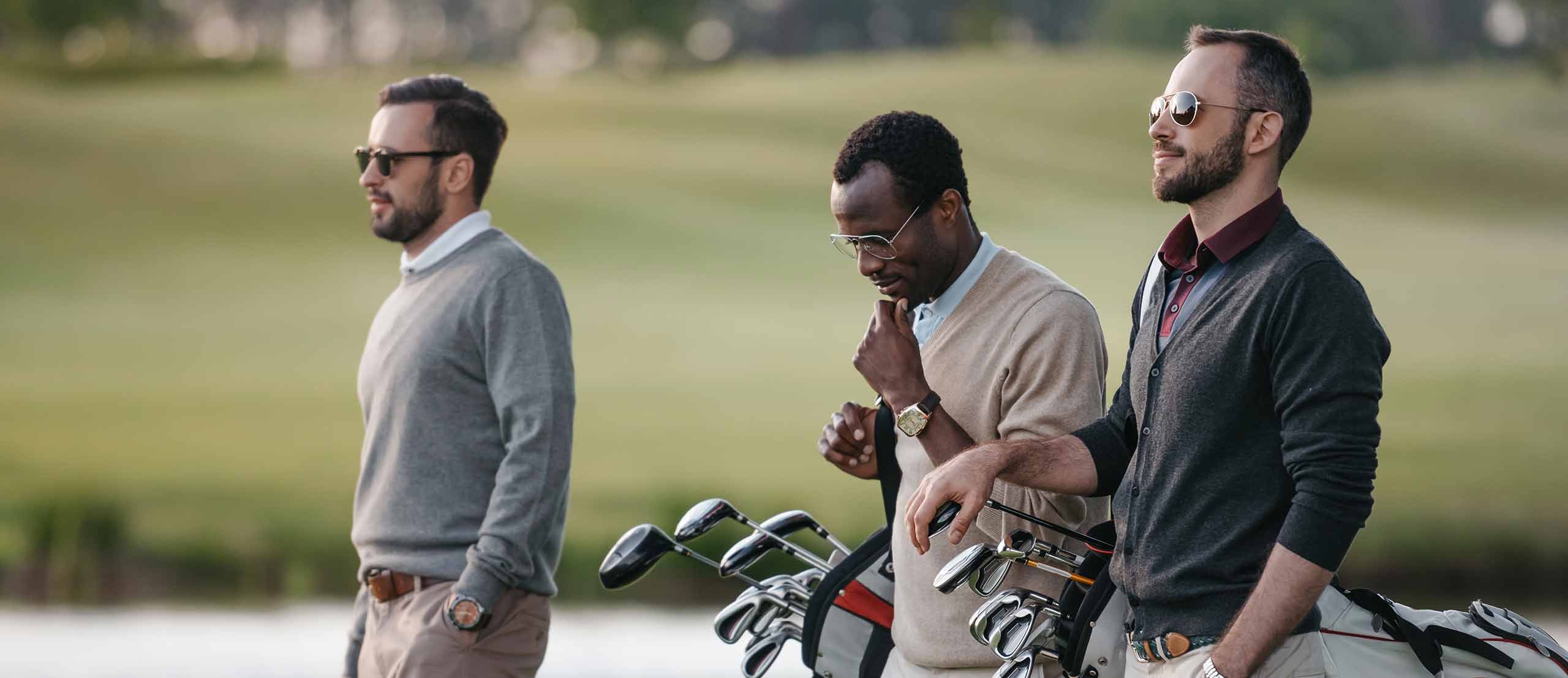 Three men in knitwear on a golf course