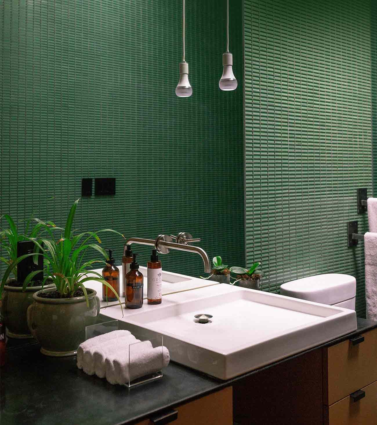 A basin in a bathroom tiled in green