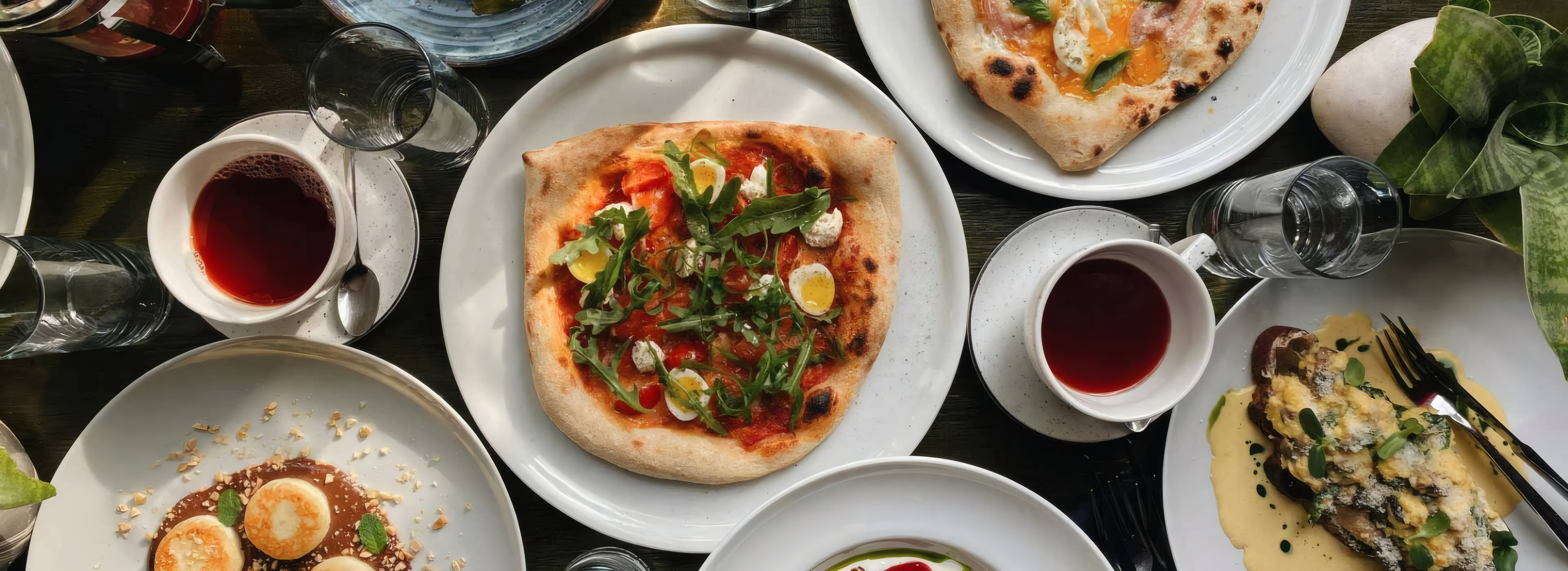 A table seen from above: pizza, tea and plates to share