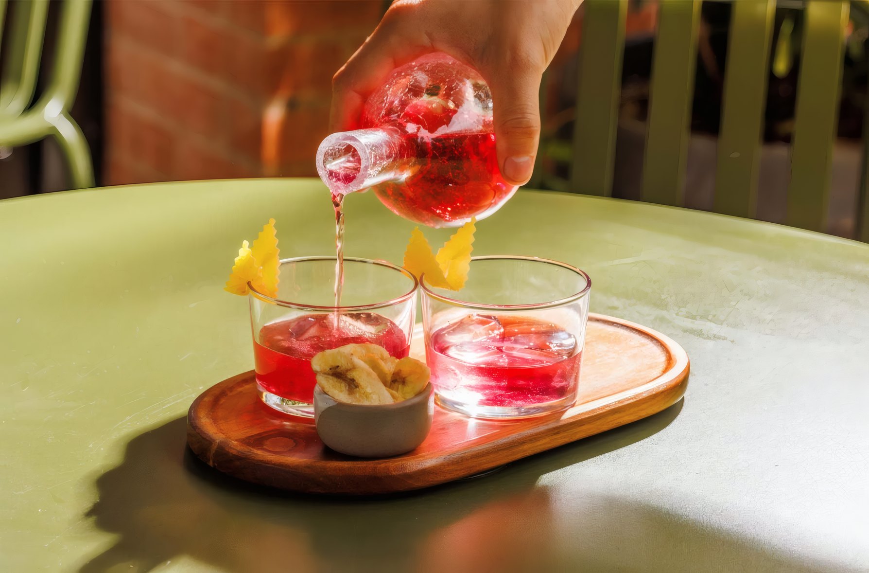 A pink cocktail poured over ice at the bar