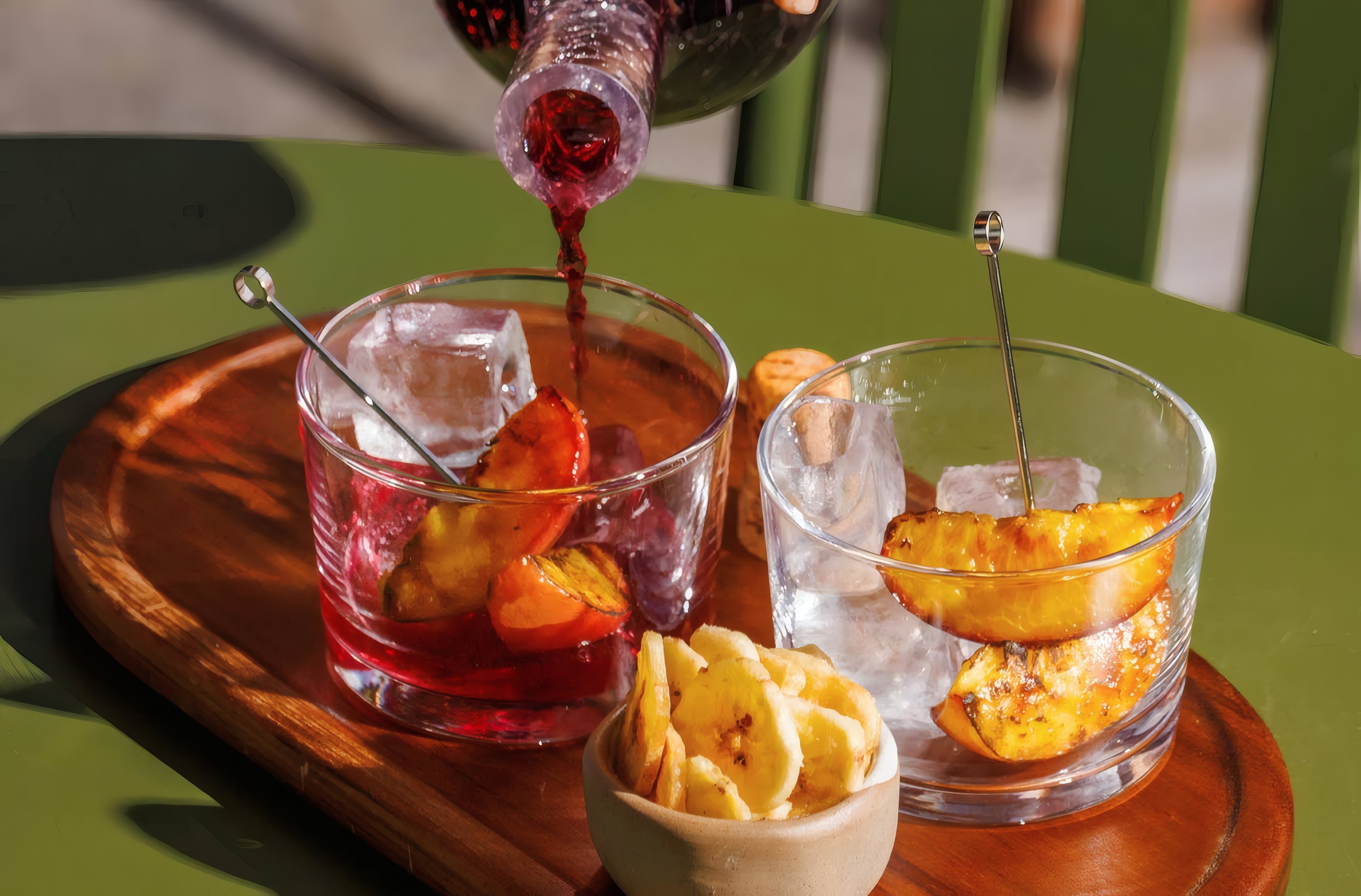 Spritzes and small plates on a green table in the afternoon sun