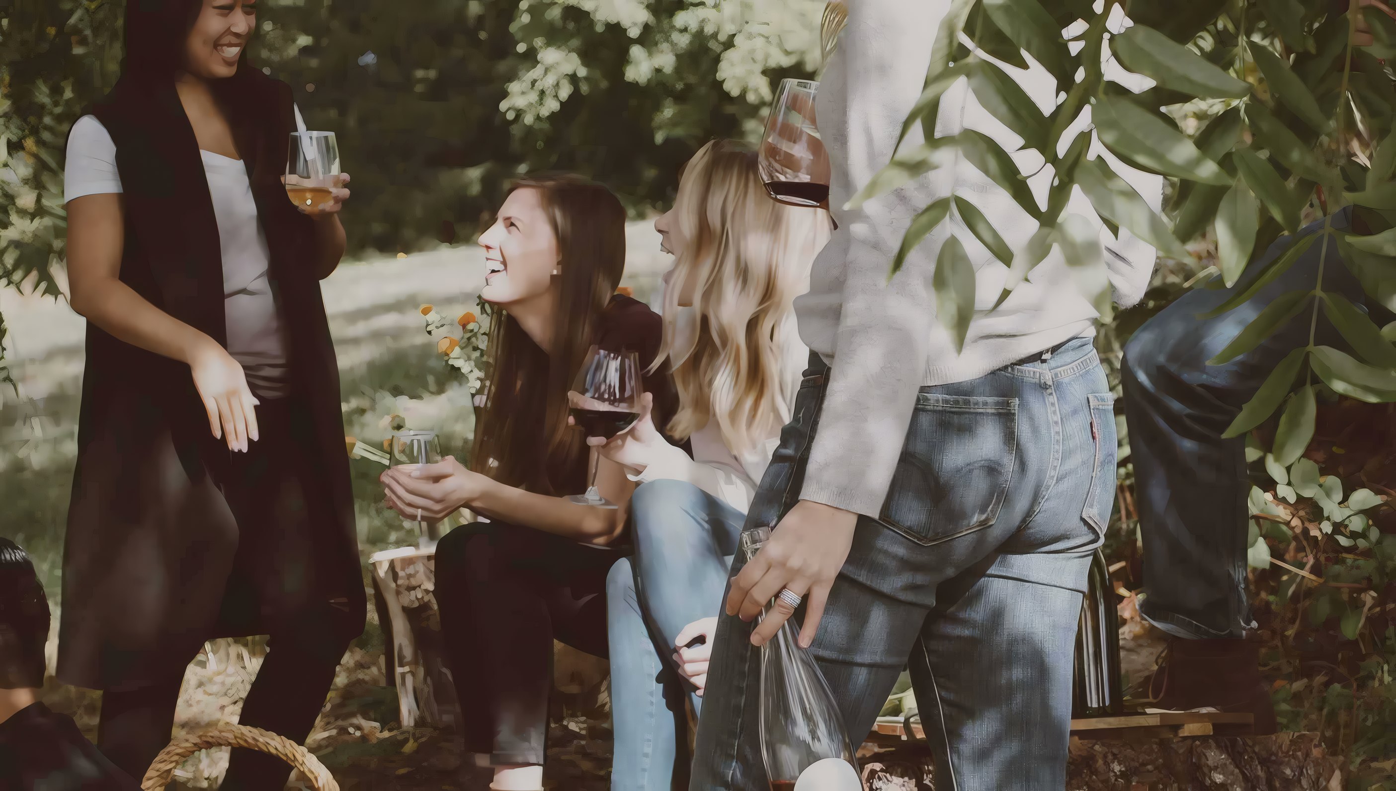 Two members walk between the vines with their glasses at sunset
