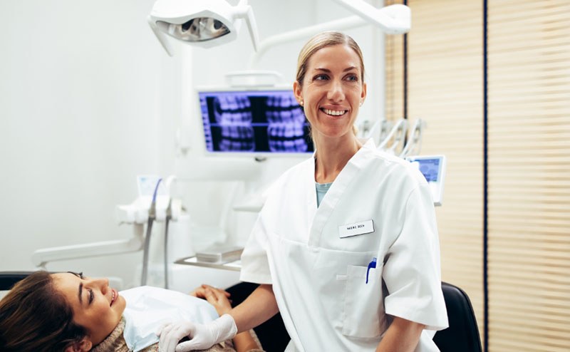 A dentist beside a patient in the treatment room