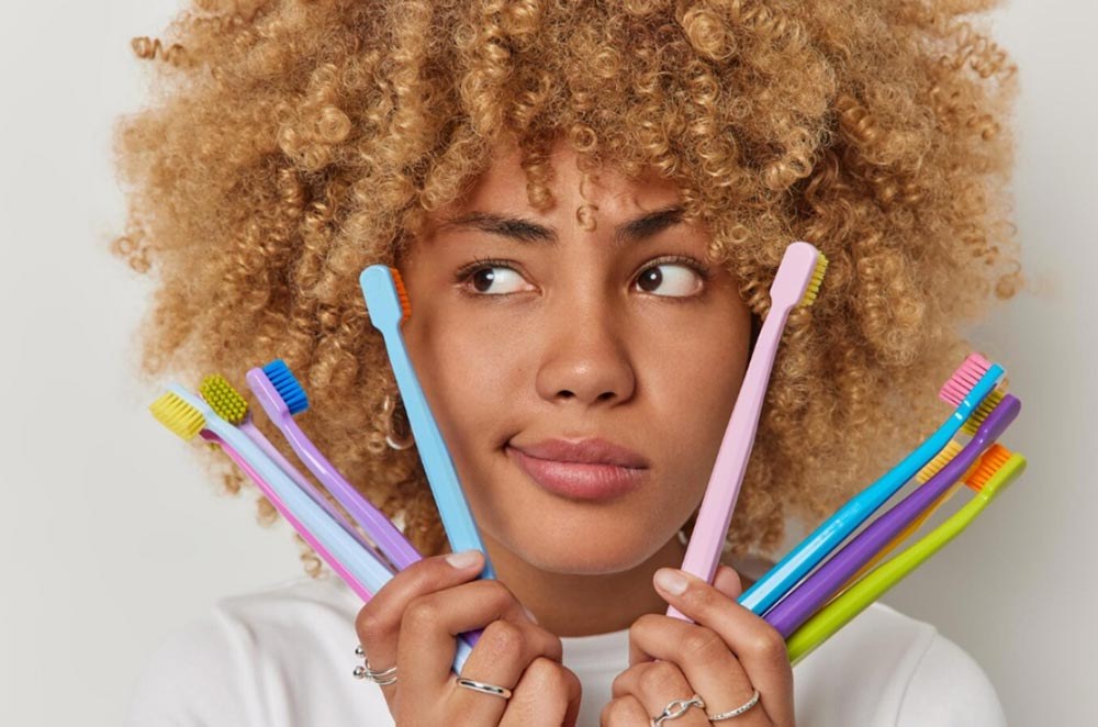 A girl holding a fan of colourful toothbrushes