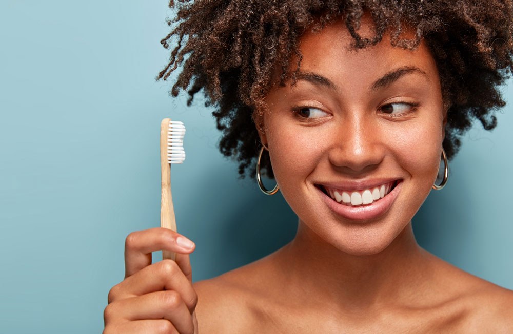A woman smiling with a bamboo toothbrush