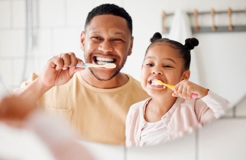 A father and daughter brushing their teeth