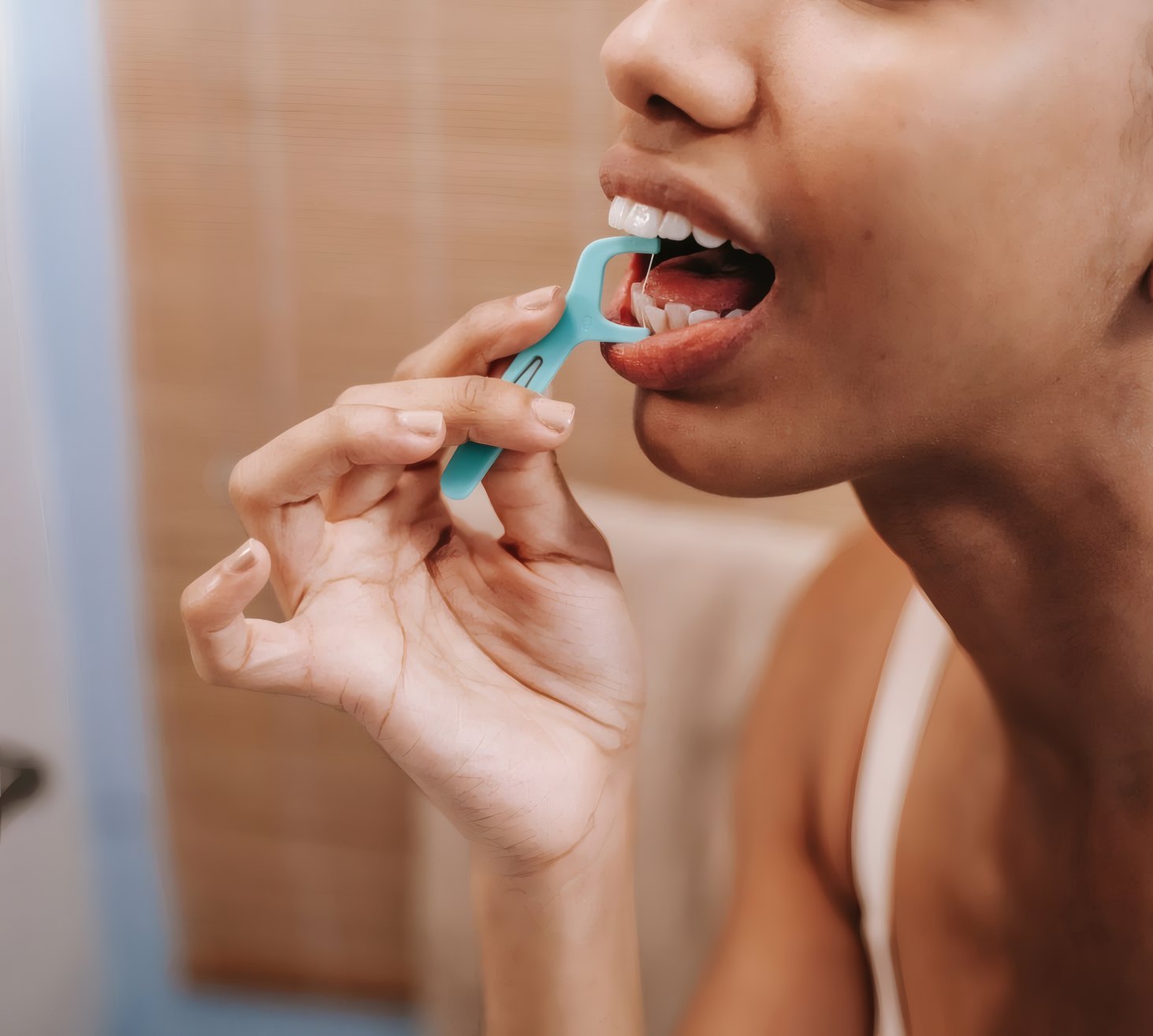 A woman cleaning her teeth with a floss pick