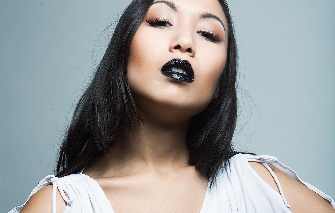 A model in black lipstick and a white dress, cast for the shows