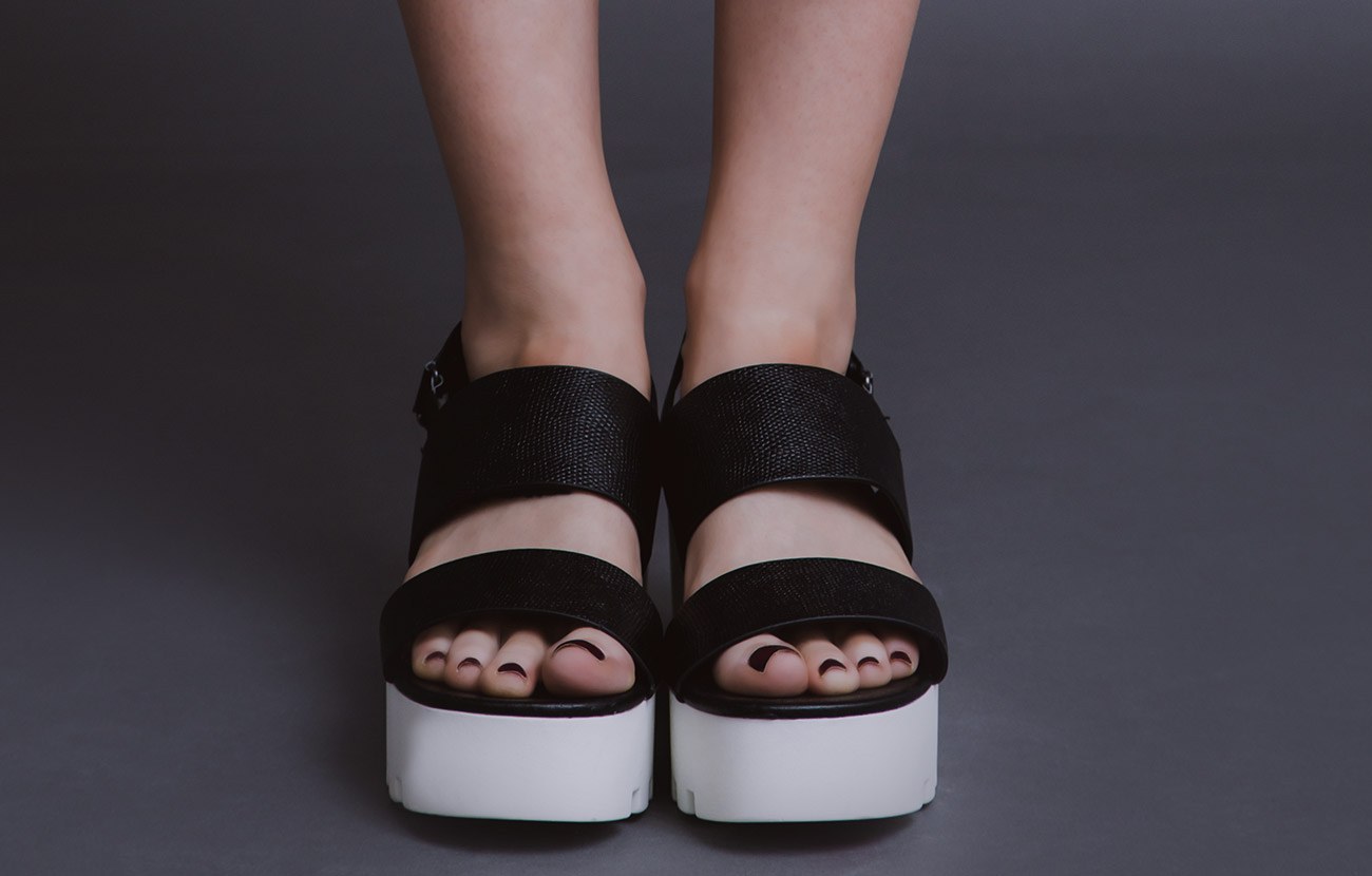 Black platform sandals on a grey floor