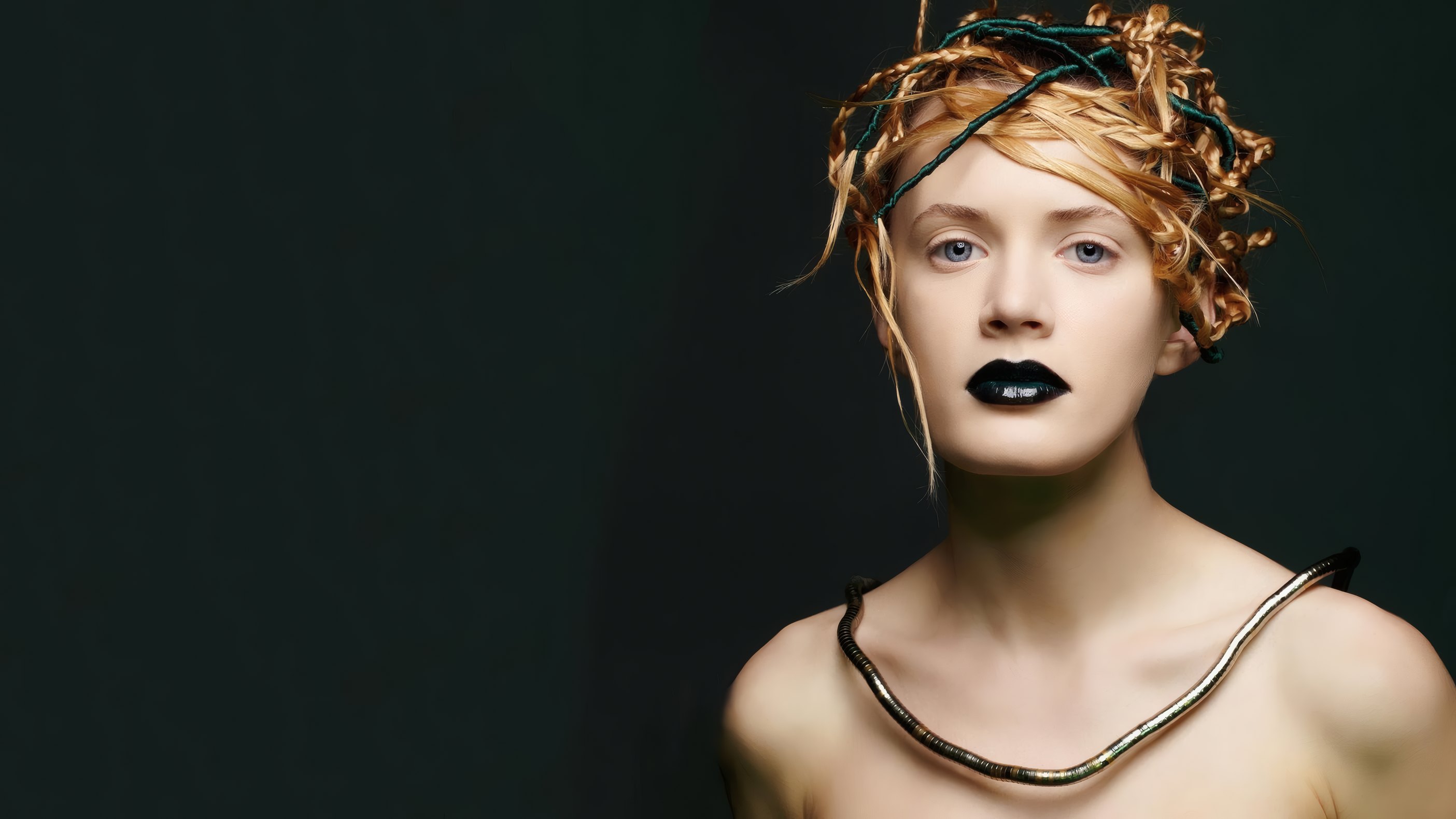 A model in gold-braided hair and black lipstick on a dark studio ground
