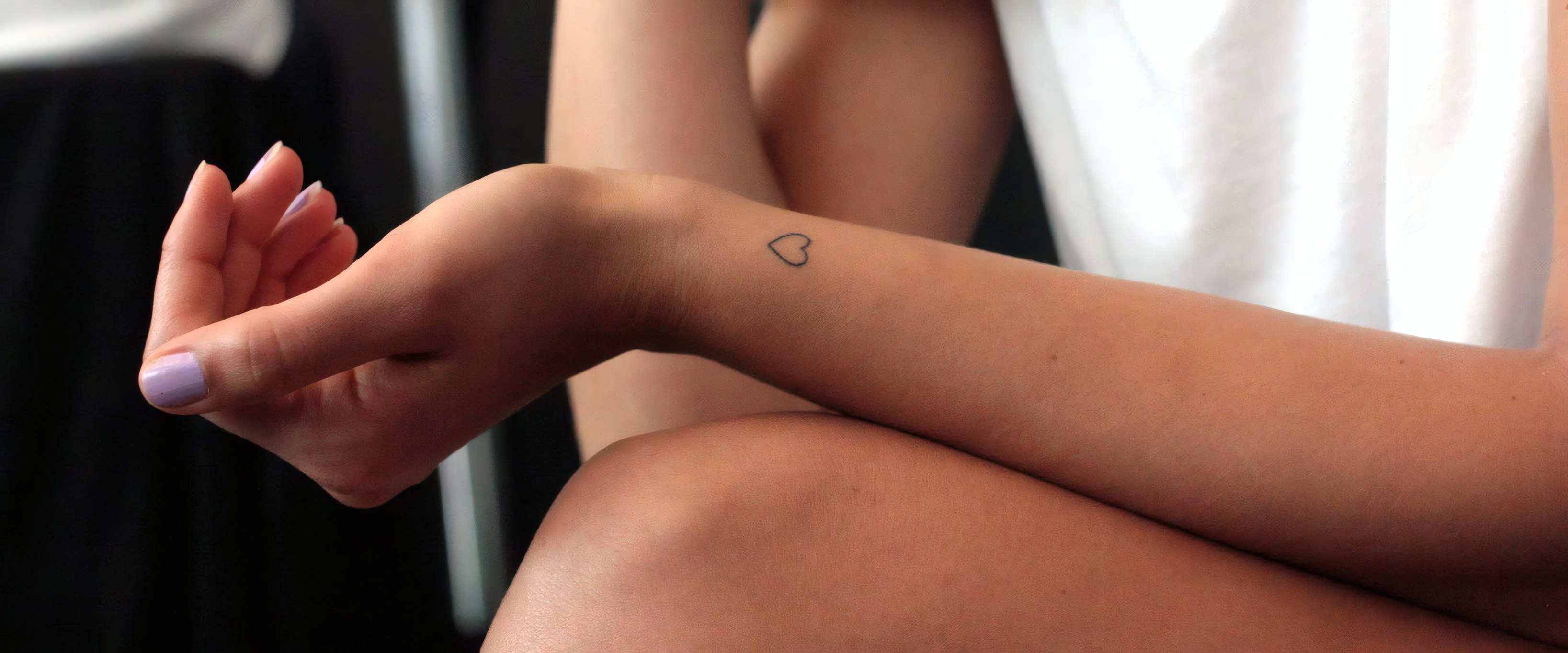 A tiny fine-line heart on a wrist