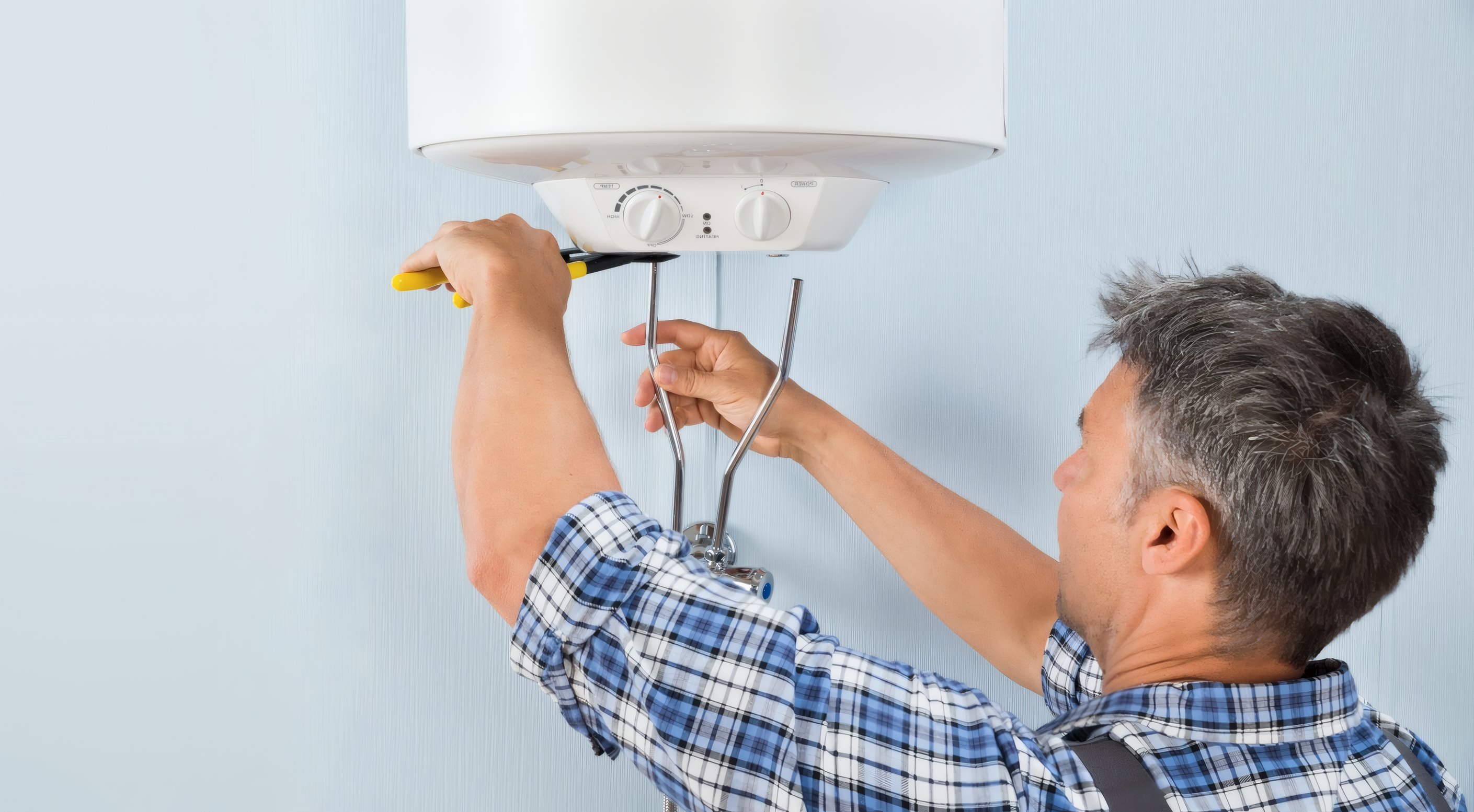 A fitter working on a wall-hung water heater
