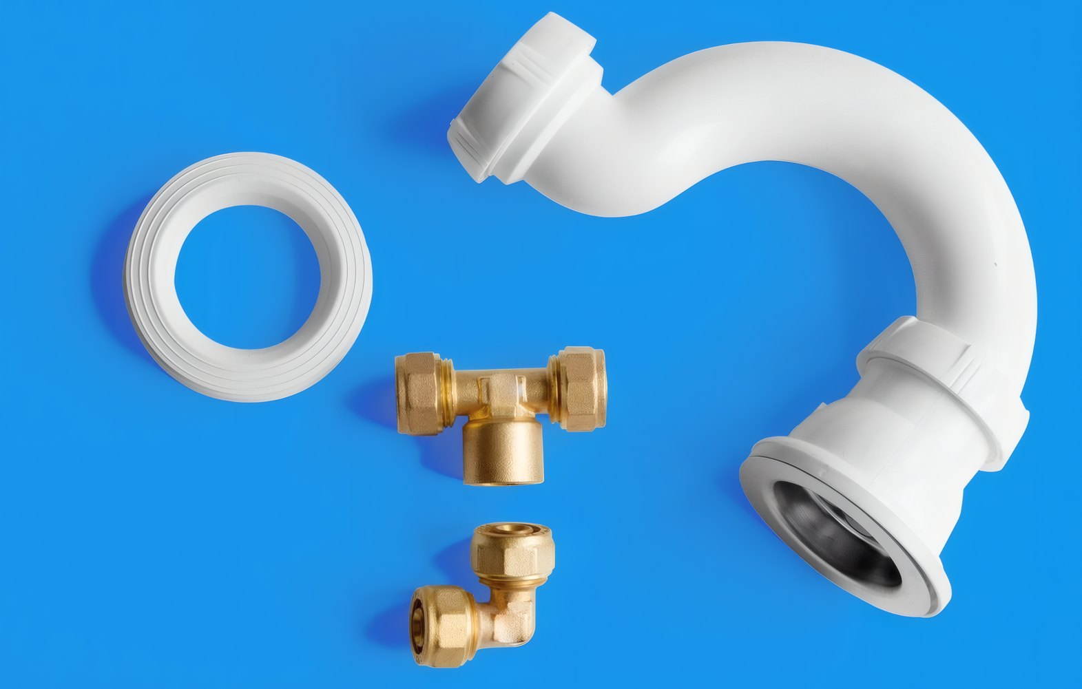 A white trap, a valve and fittings laid out on blue
