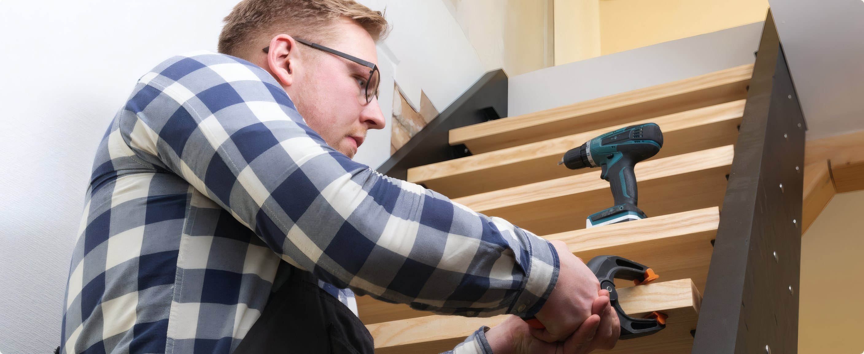 A carpenter refitting stair treads with a drill