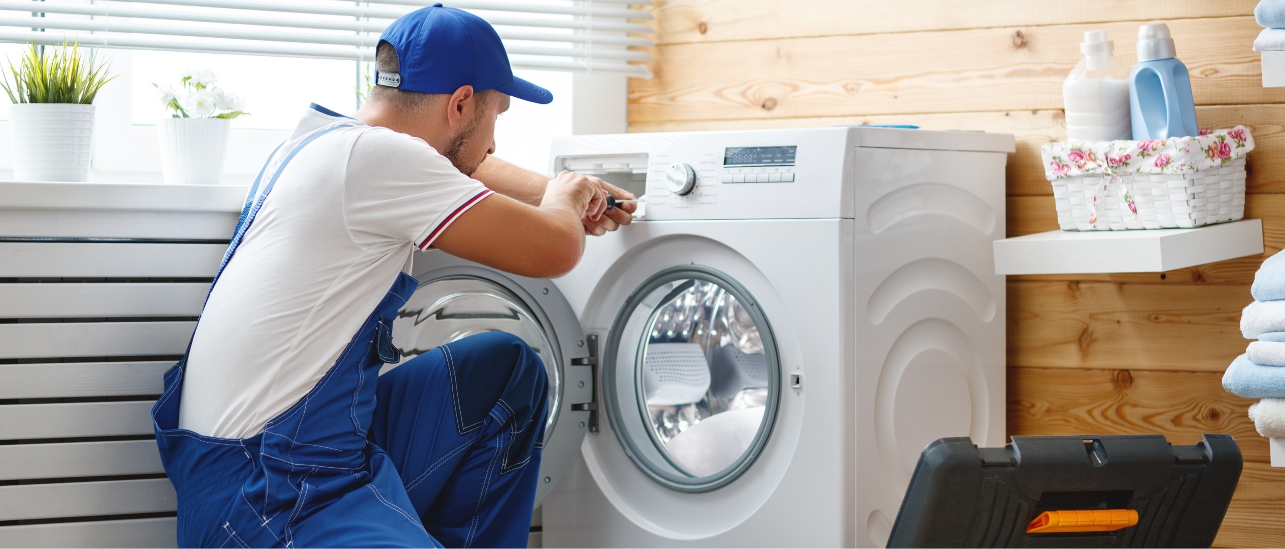 A fitter repairing a washing machine in a laundry room