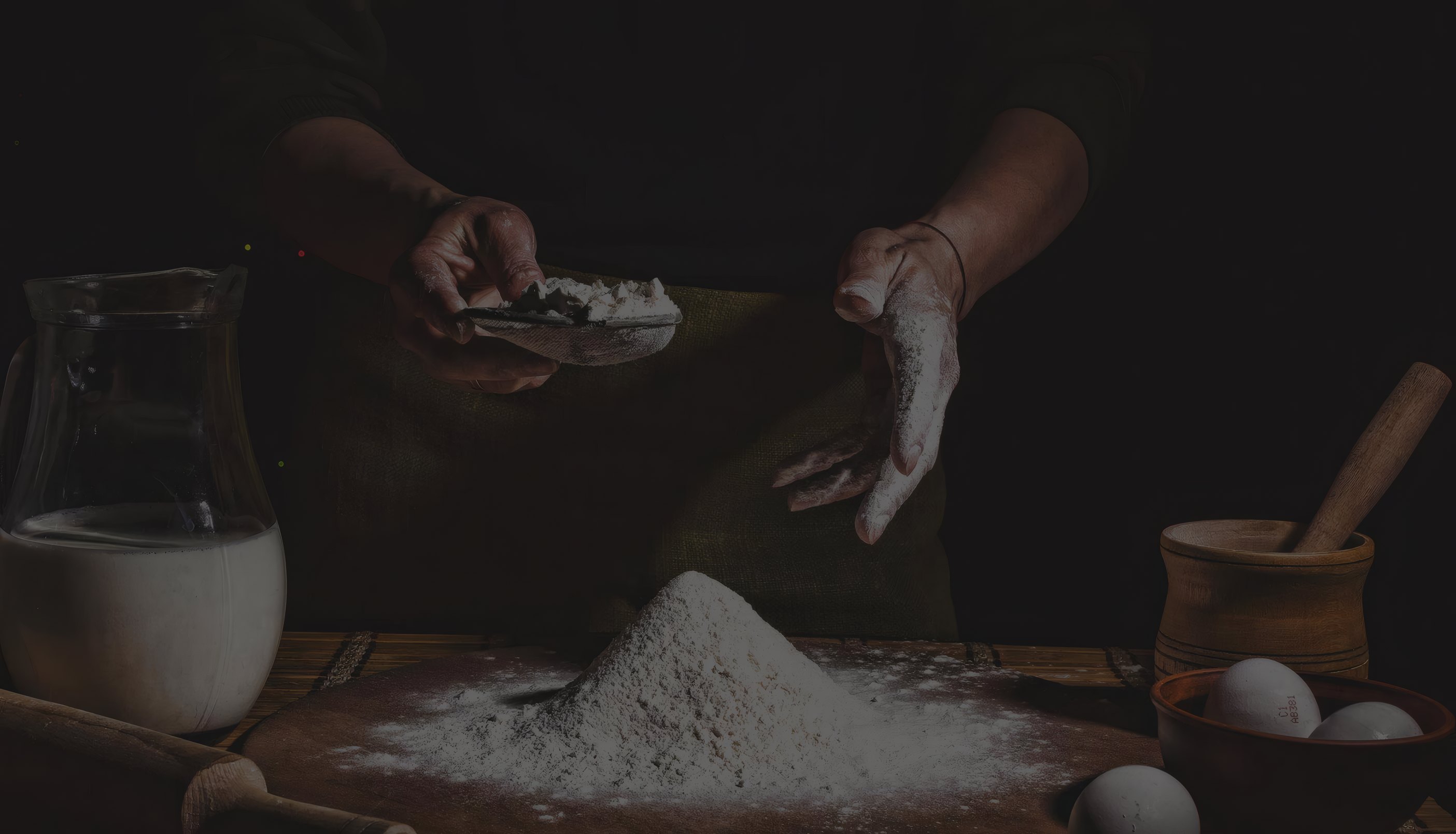 A baker's hands dusting flour over the bench at night