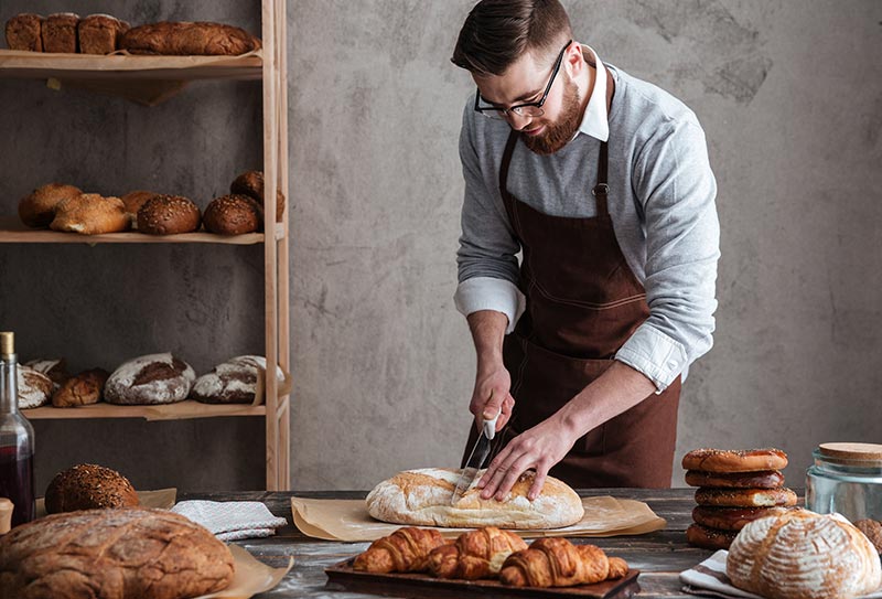 A baker scoring loaves at the bench