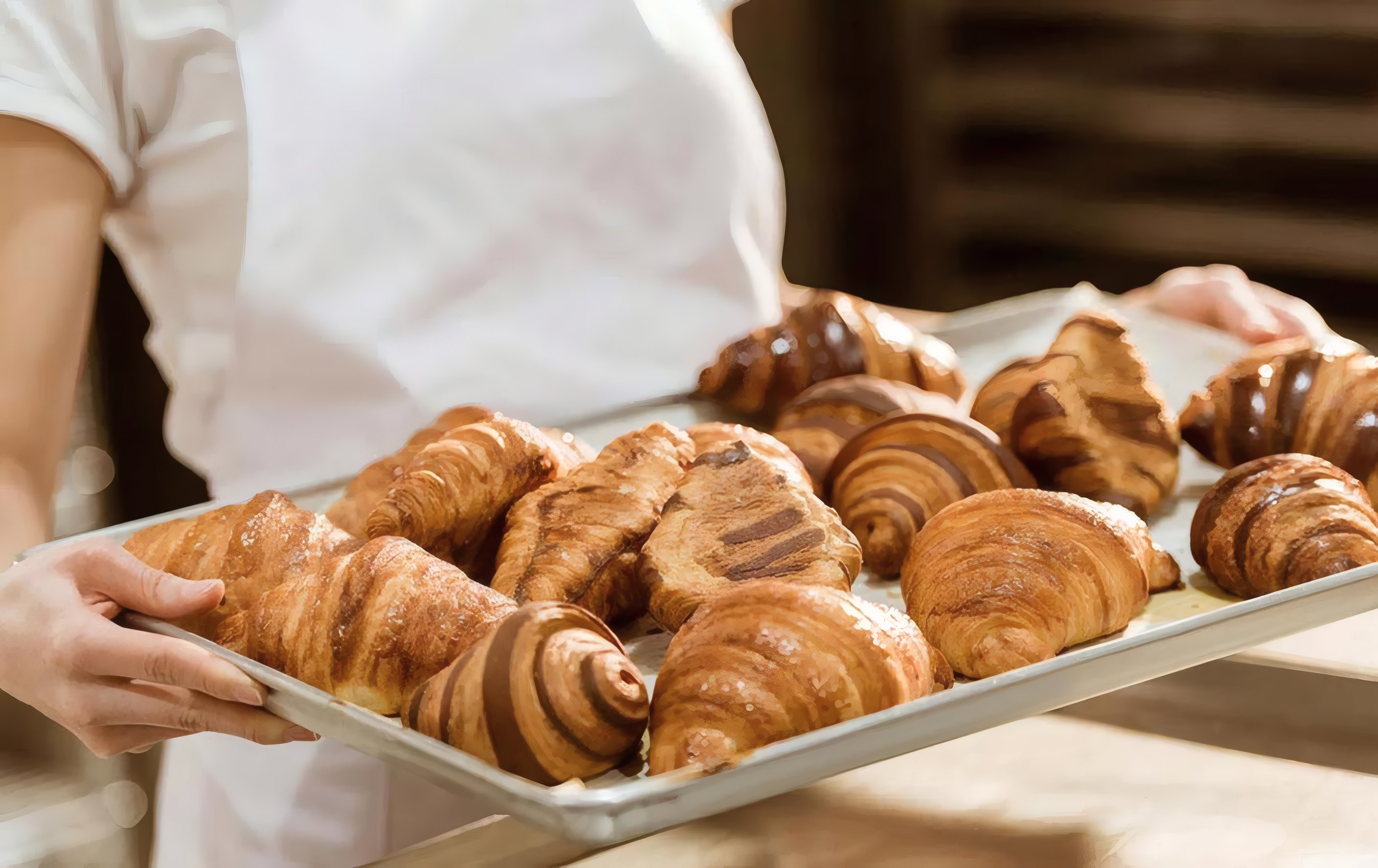 A tray of croissants held by a baker