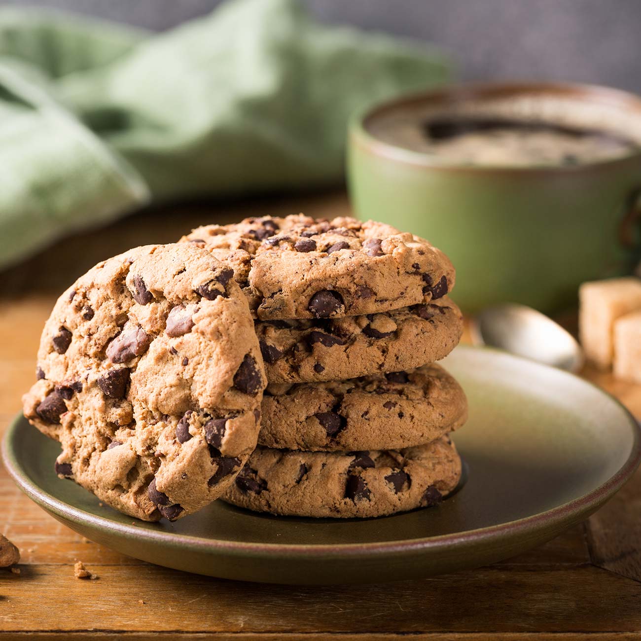 Chocolate cookies stacked beside a green mug