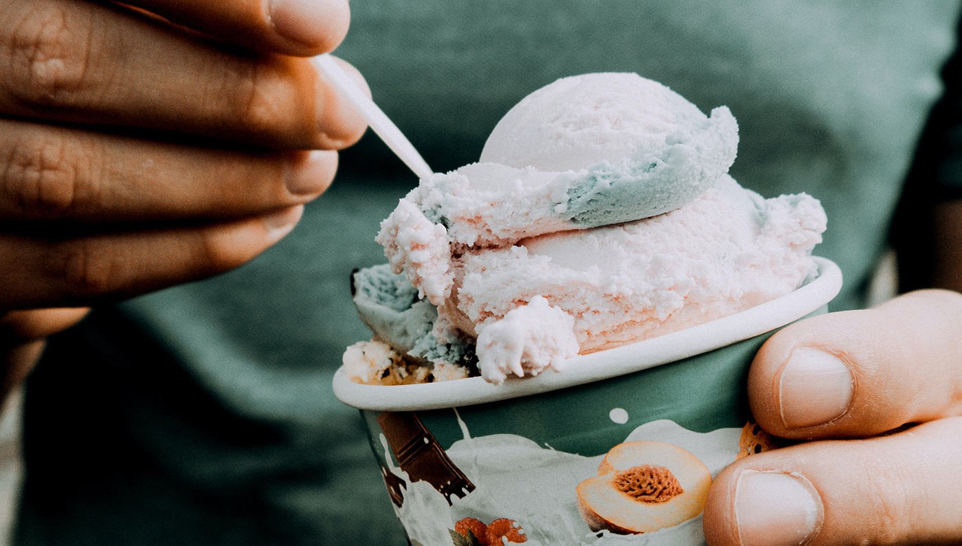 A cup of pastel gelato with a spoon