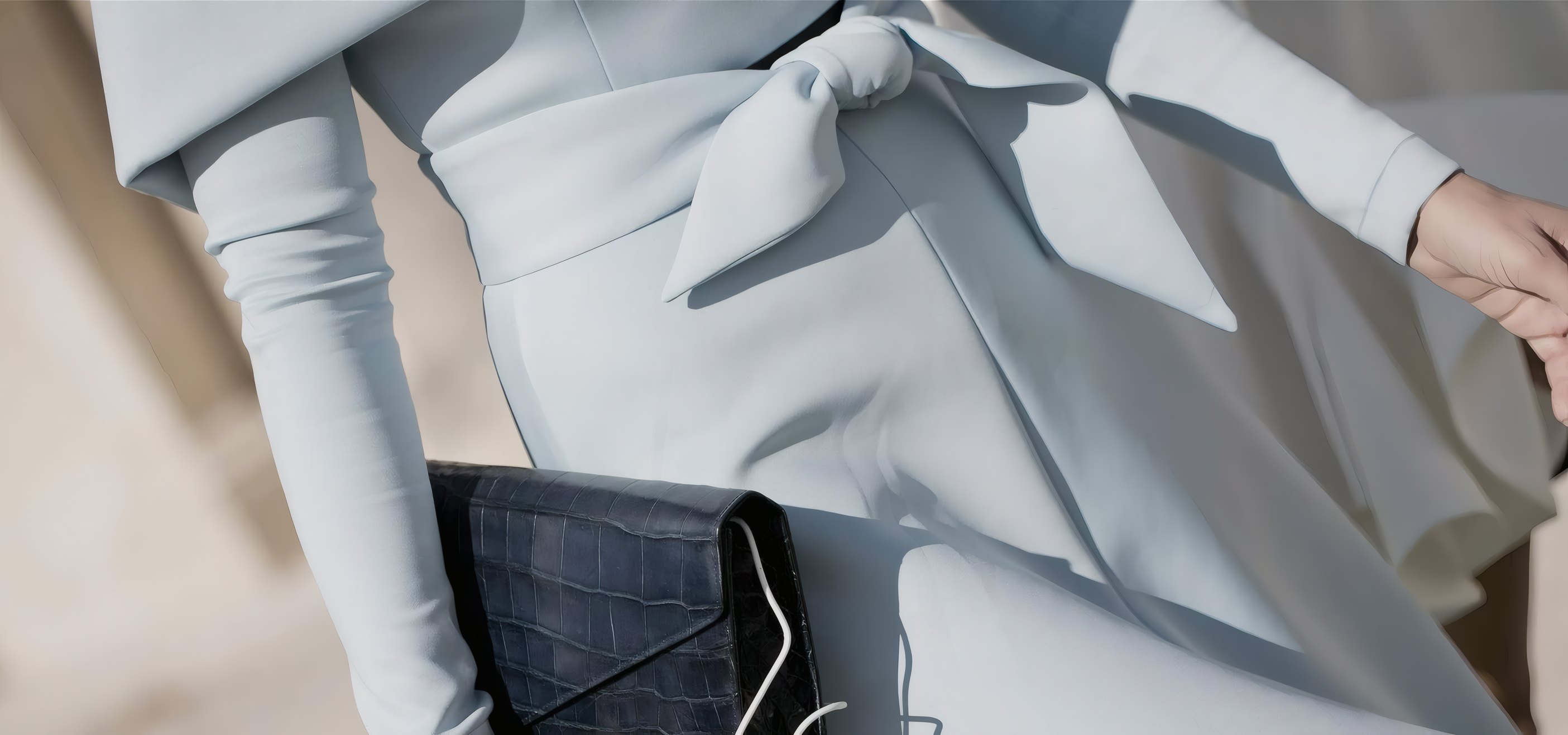 A powder blue dress tied at the waist, a dark clutch in hand