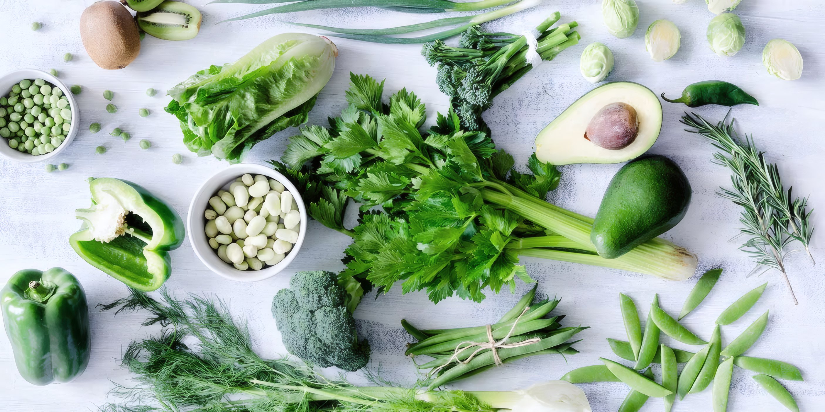 Fresh greens, beans and herbs on a white table