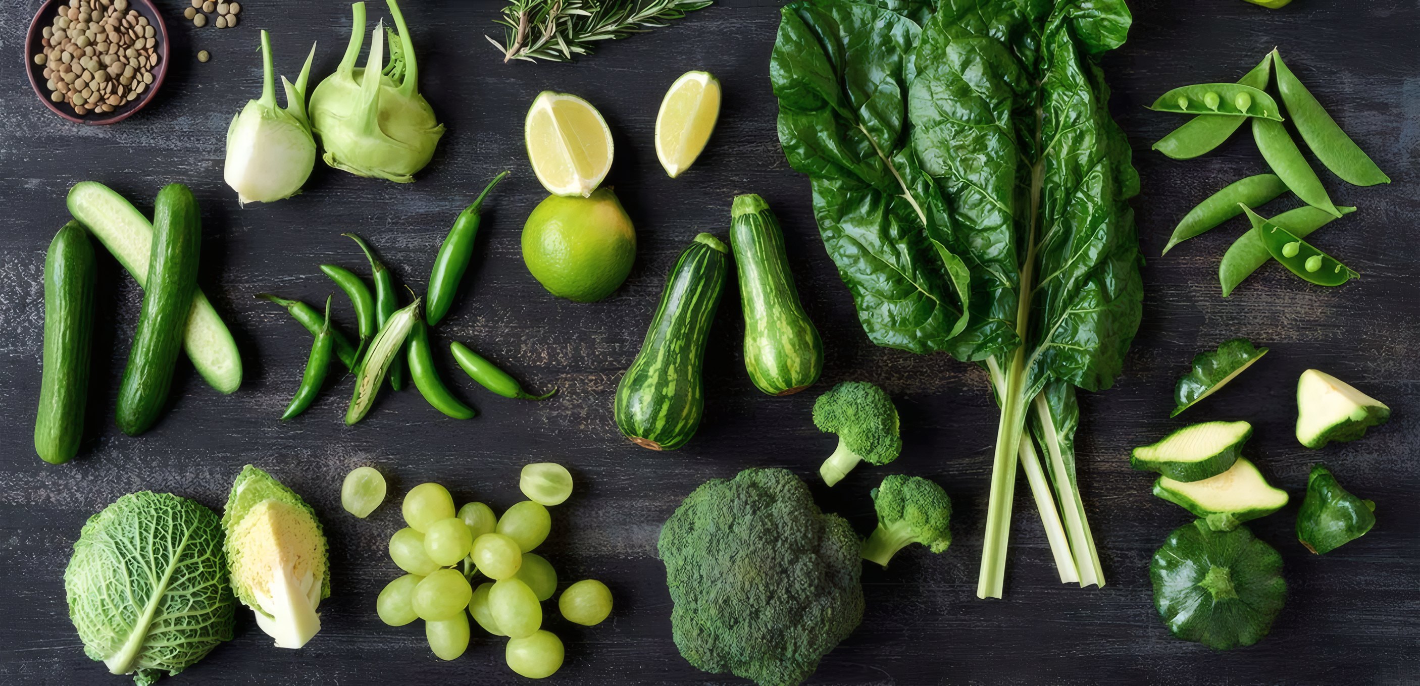 Green vegetables laid out on dark slate